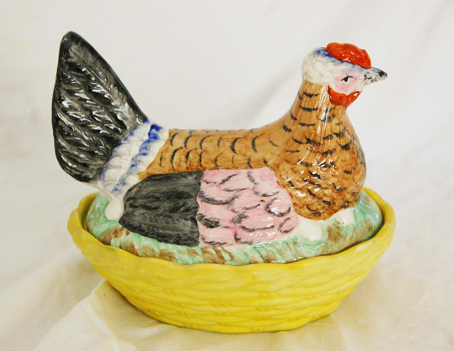 English Staffordshire ironstone chicken on a yellow basket. This hand painted chicken and basket are multi colored, the chicken having feathers in pink, a little blue, white, black and light chocolate brown with black feather detailing, sitting on