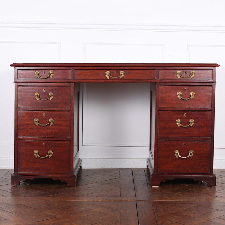 English Mid-Victorian double-pedestal desk in Cuban mahogany, the pedestals with four graduated banks of drawers flanking an upper central drawer, the reverse with arched paneled doors which open to reveal shelves, the whole raised on bracket