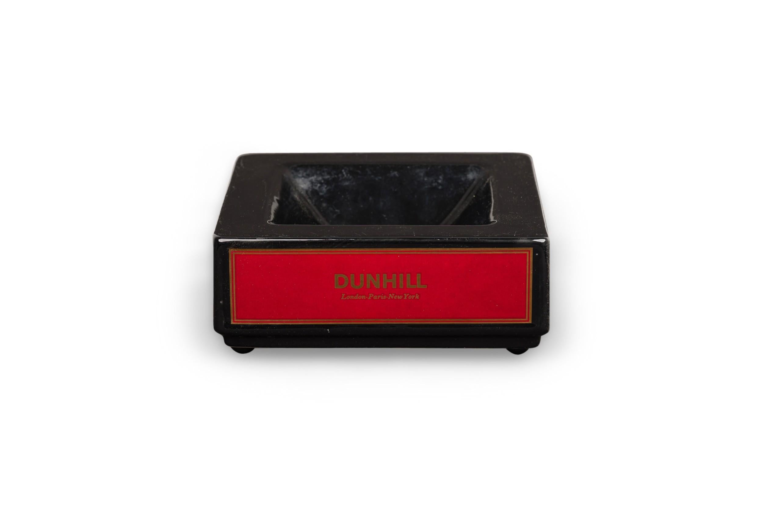 Englischer, quadratischer, schwarzer Keramik-Aschenbecher aus der Jahrhundertmitte mit dem DUNHILL-Zigarettenbrandzeichen auf allen vier Seiten in fetter, goldener Schrift auf rotem Grund (WADE PDM-England)