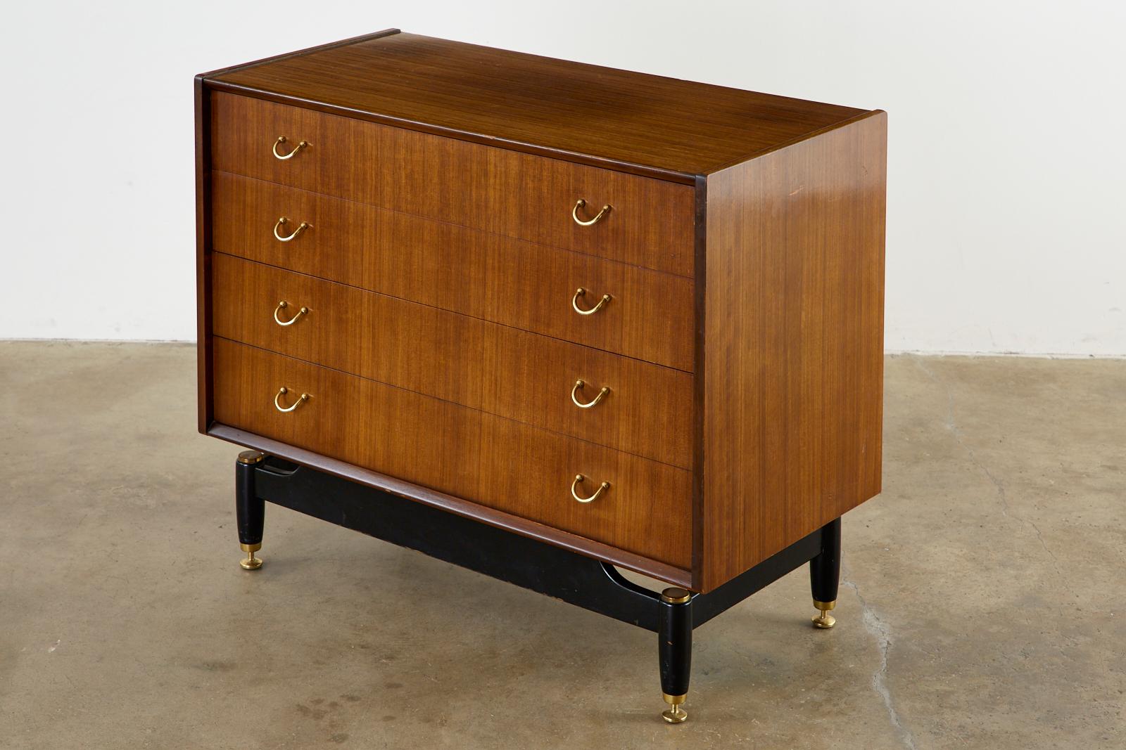 Stylish Mid-Century Modern commode or chest of drawers designed in England by G-plan for Wolfe and Hollander, London. The beautiful teak case has four large storage drawers fitted with brass pulls and is supported by an ebonized wood base having