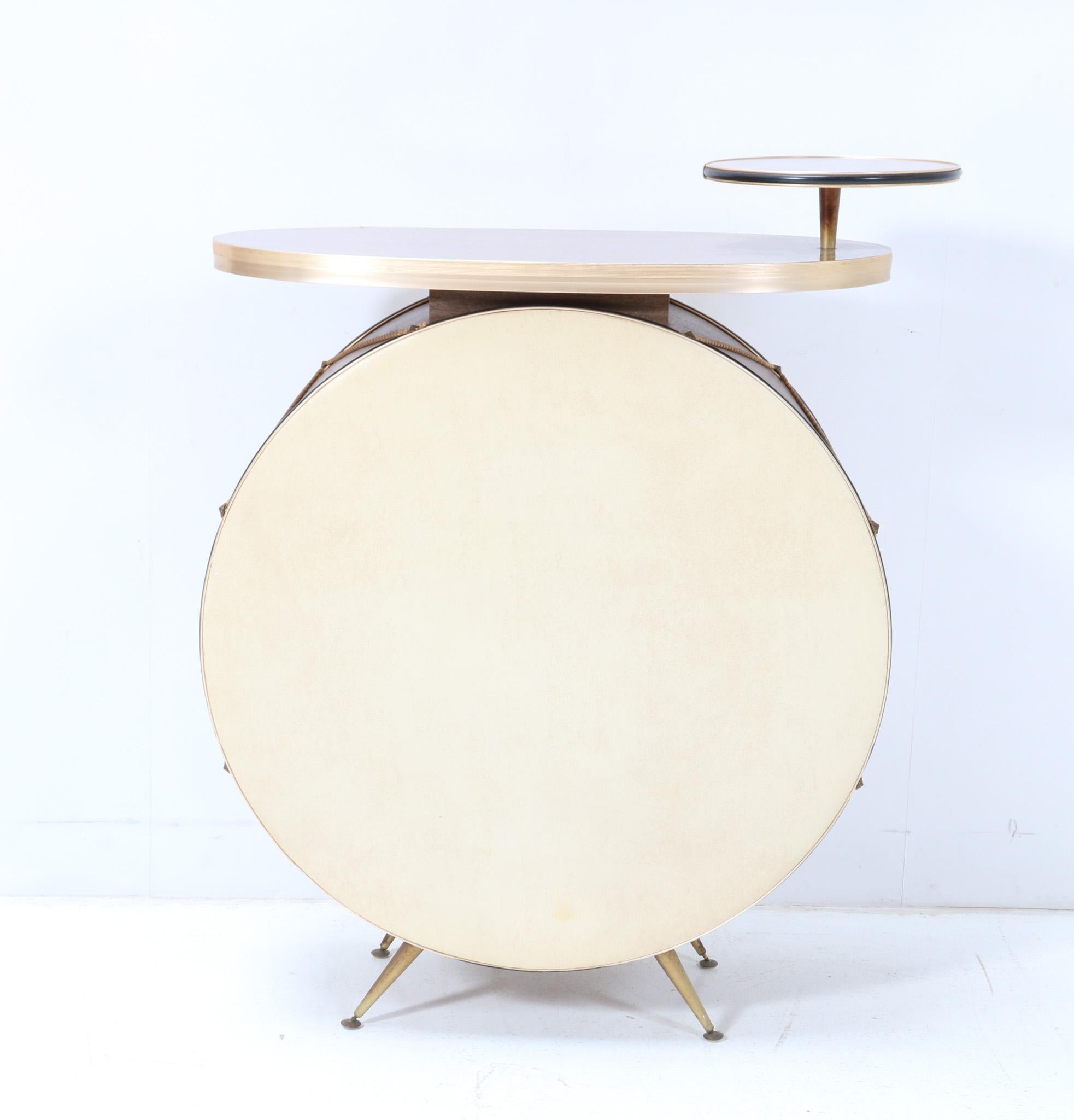 Funky and rare Mid-Century Modern drum dry bar.
Design by Barget Built UK.
Striking British design from the 1960s.
Laminated plywood drum shaped base with original laminated plywood tops.
On original gilt metal feet.
Marked with original