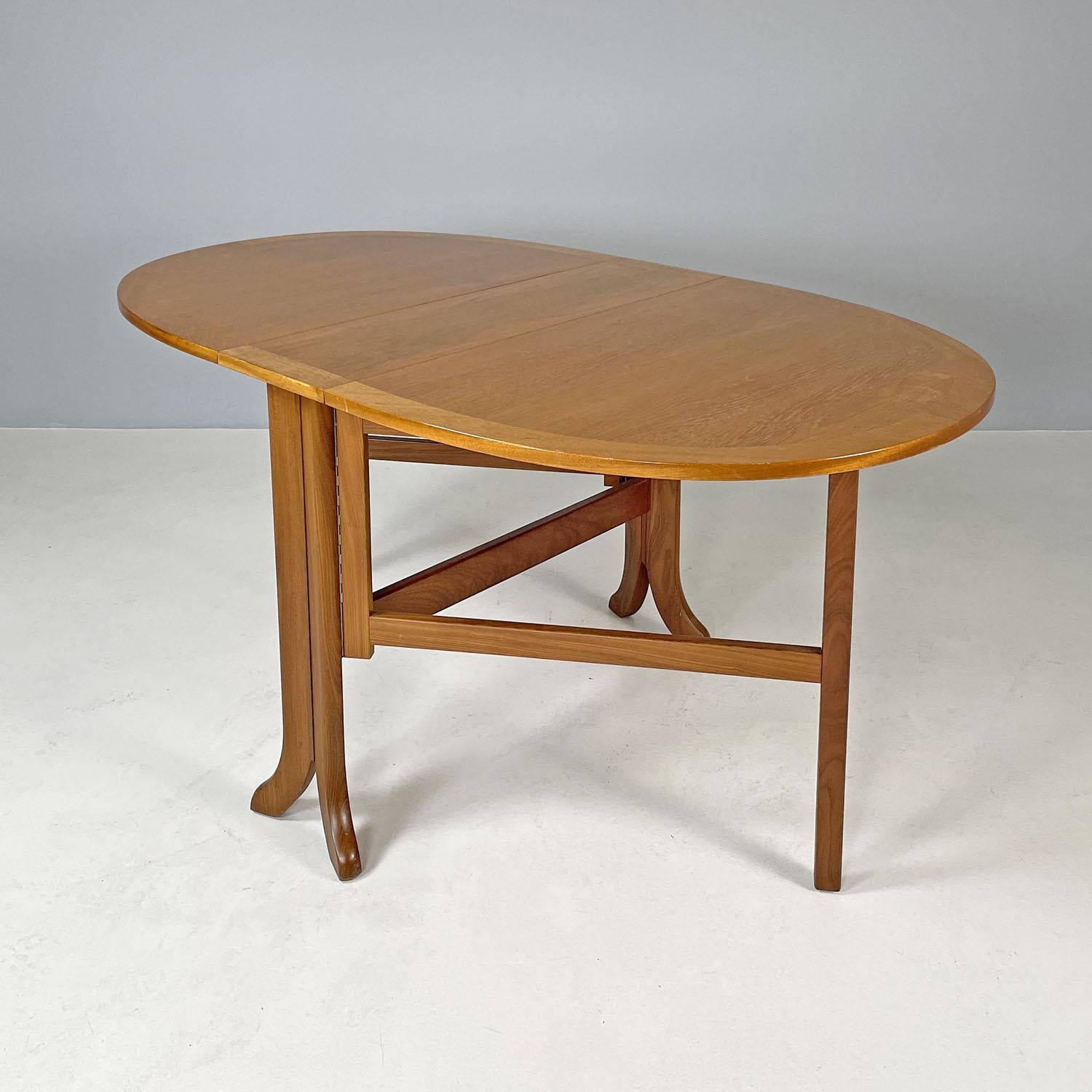 English mid-century modern wooden dining table with flap doors, 1960s
Dining table made entirely of wood. It has a fixed rectangular central top, which corresponds to two lateral semicircular folding doors, so that once both are opened the table has