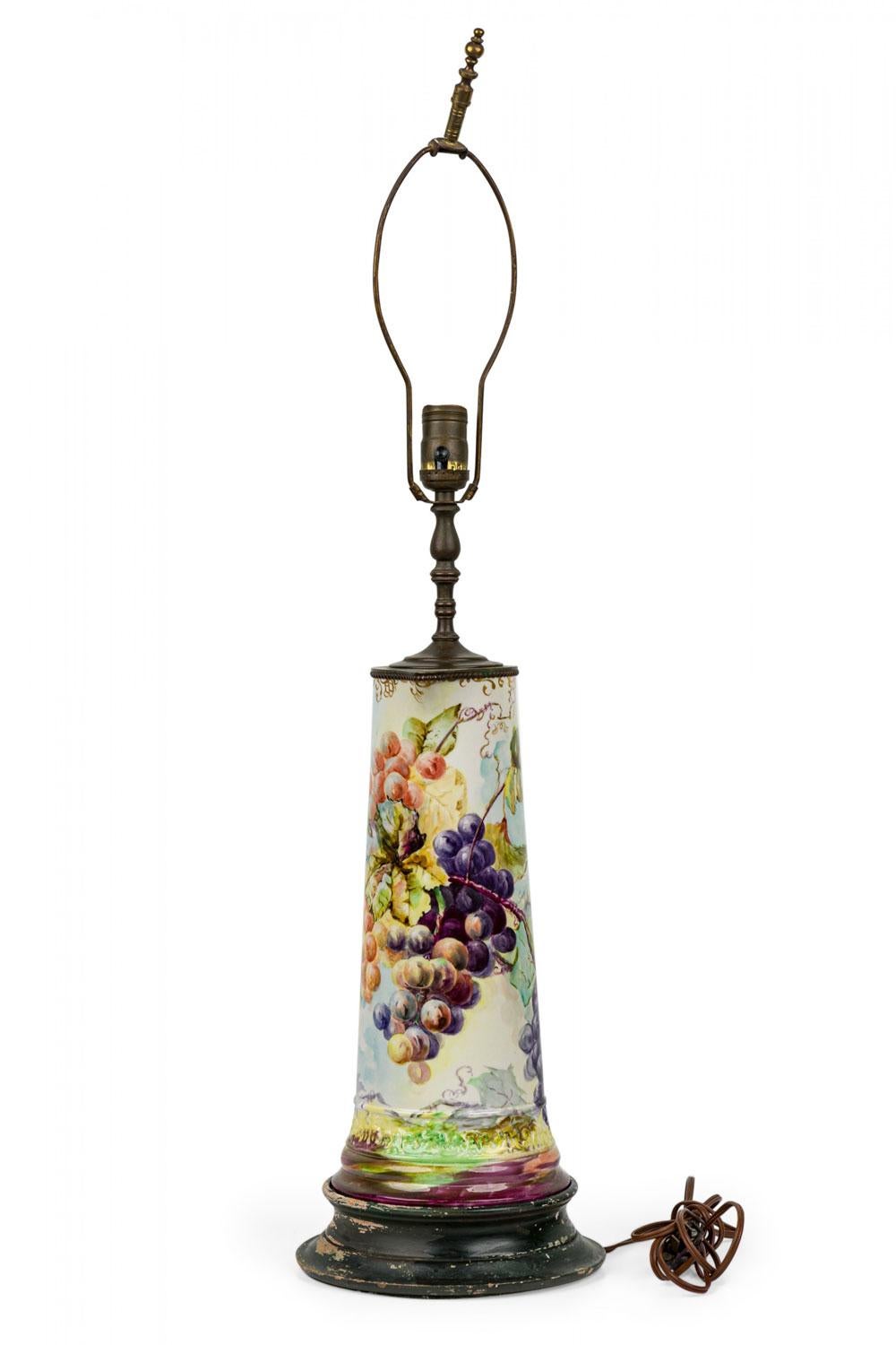 English Mid-Century table lamp with a beige ceramic pitcher form body with a grape and vine motif, resting on a brass base and mounted with brass hardware.

Ships without shade.