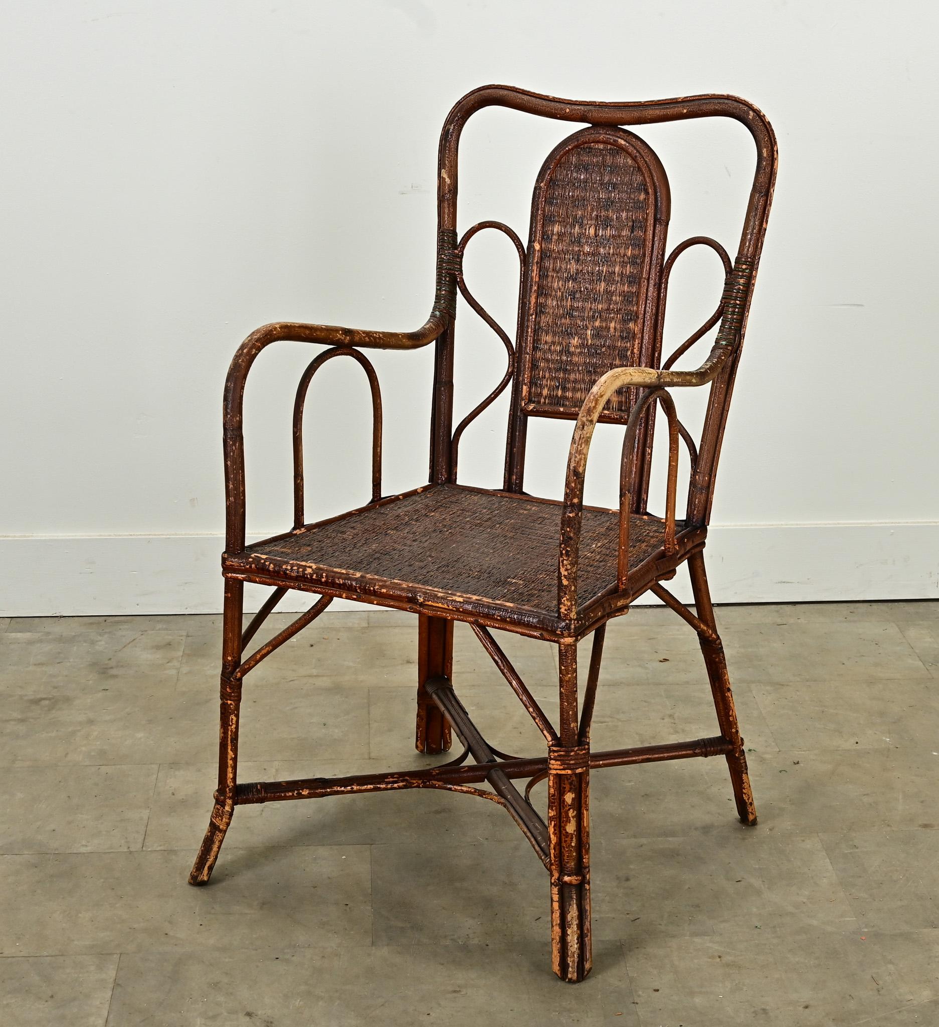 Fauteuil en rotin anglais du milieu du siècle. Le cadre de cette élégante chaise est incurvé et relié à des panneaux de rotin tressé qui forment le dossier et l'assise de la chaise. Confortable, robuste et attrayante, cette chaise est prête à être