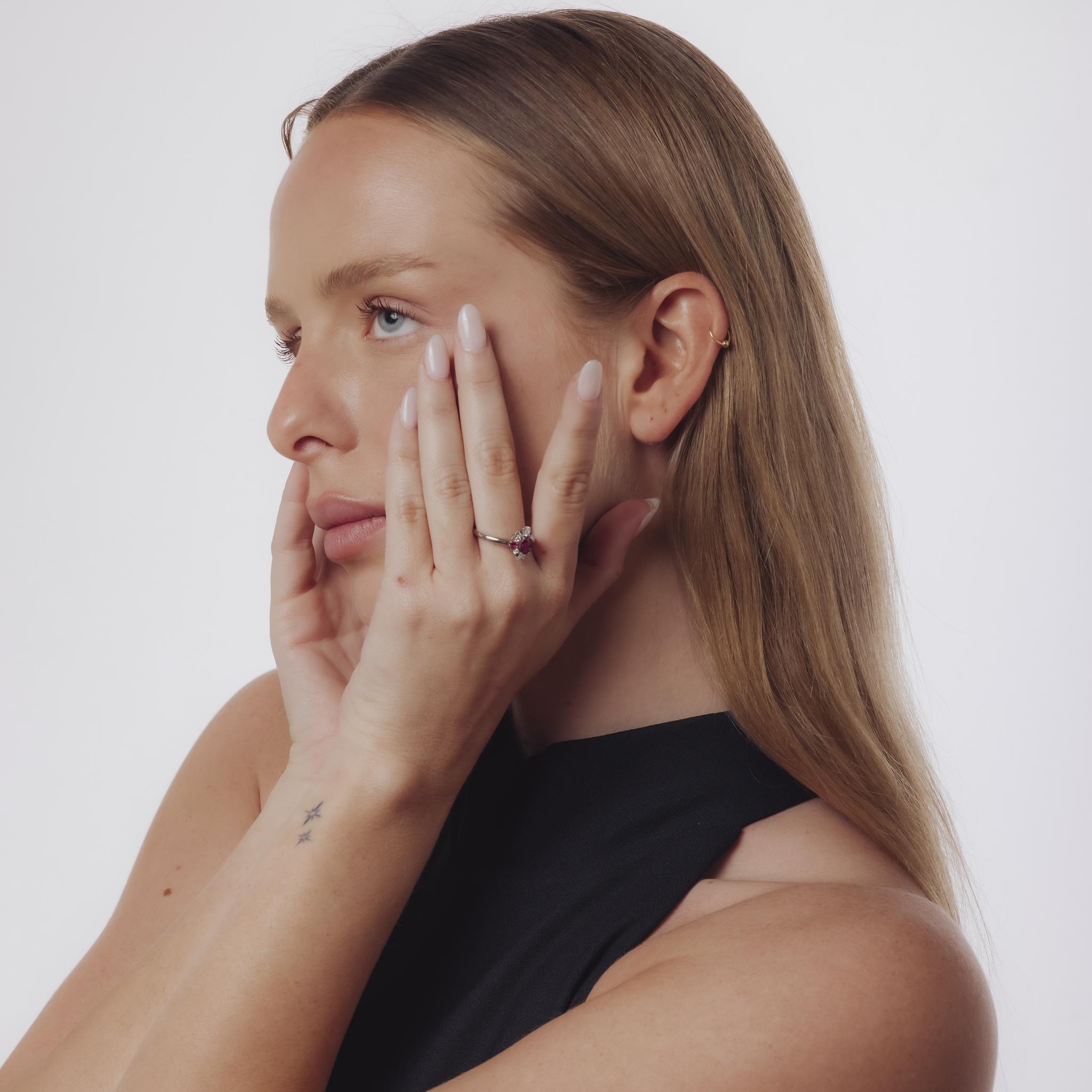 Un raffinato anello in platino di metà secolo con al centro un rubino ovale, accentuato da rubini a losanghe e diamanti scintillanti di colore G-H di purezza SI per una raffinatezza senza tempo.