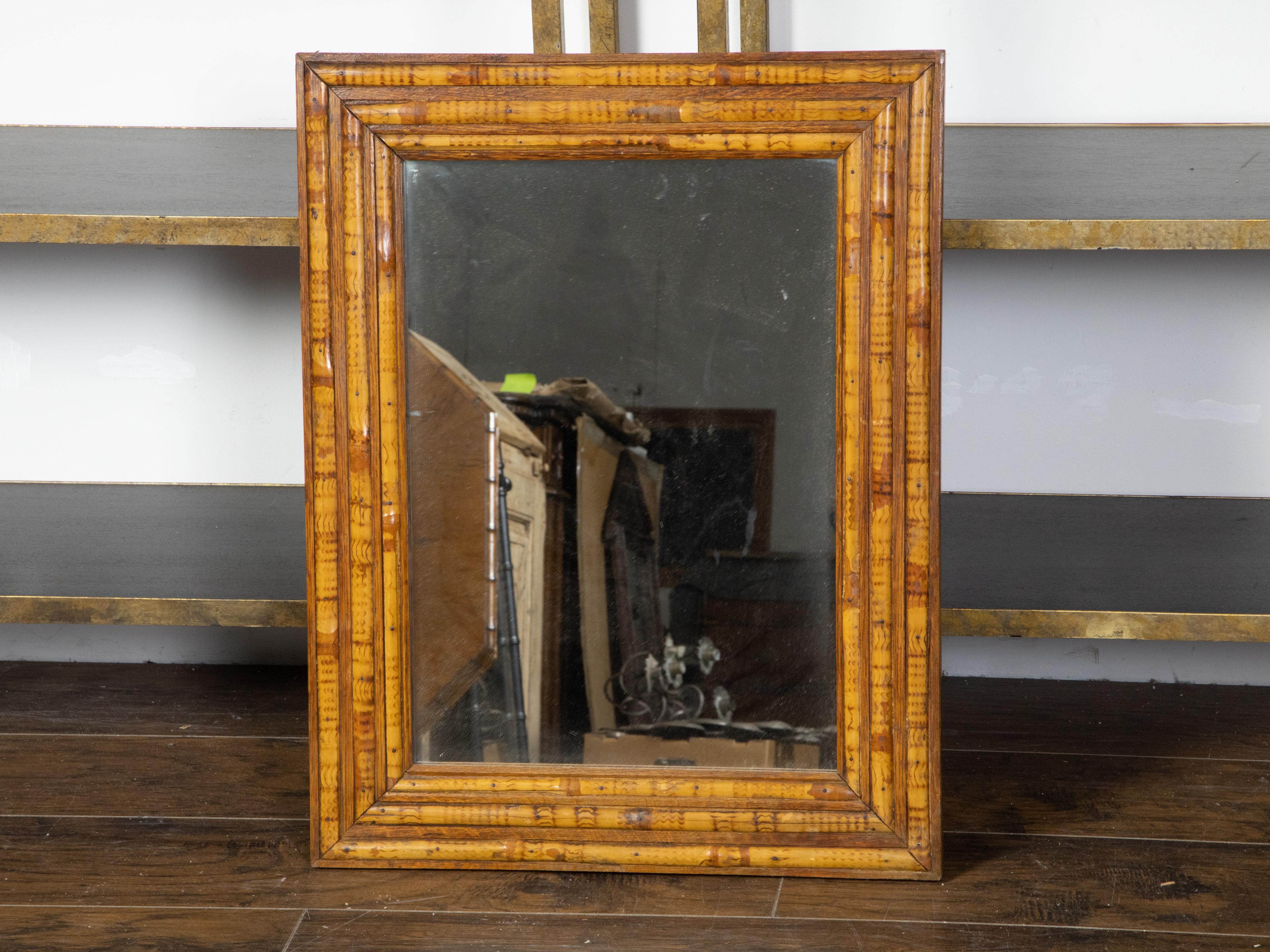 A vintage English rectangular bamboo and wood mirror from the mid 20th century, with alternating design and distressed appearance. Created in England during the Midcentury period, this rectangular mirror captures our attention with its rustic appeal