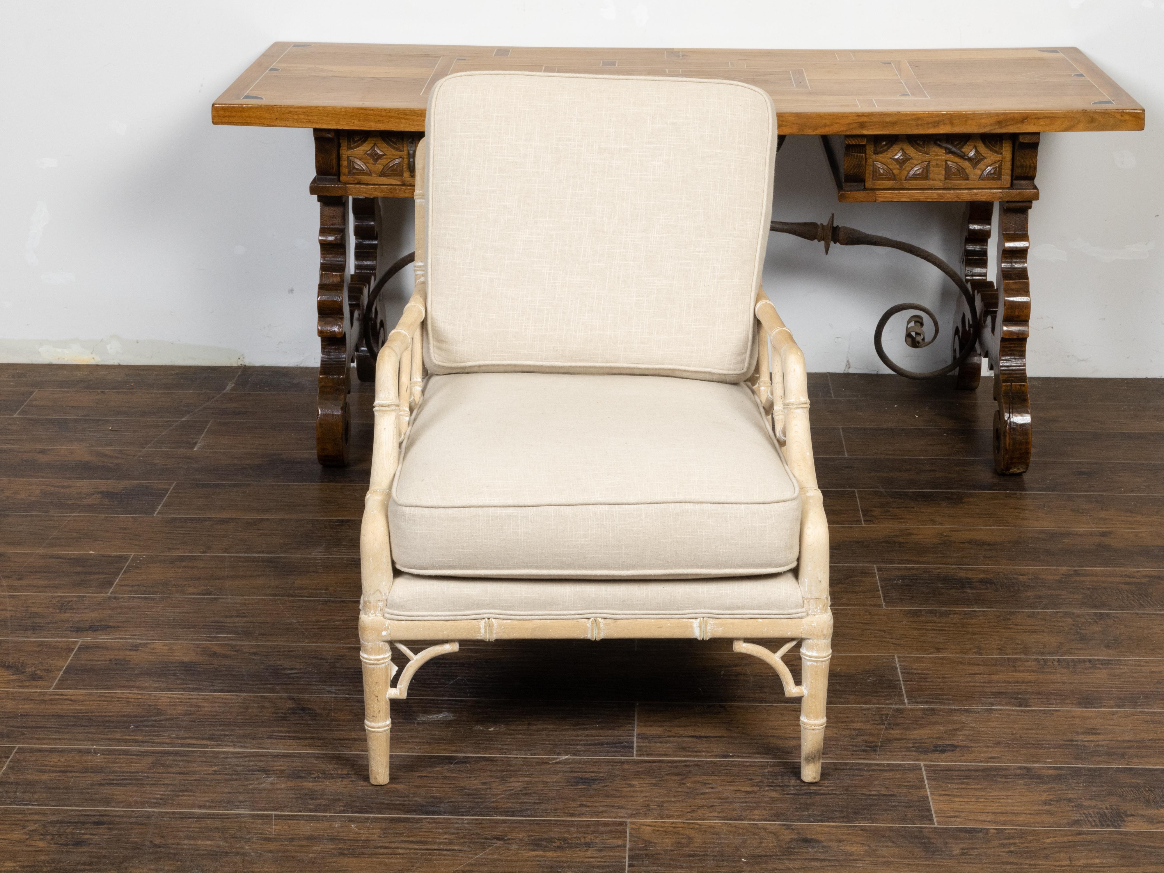 A rustic vintage English Chinese Chippendale style lounge chair from the mid 20th century, with bleached faux bamboo structure and new linen double welt upholstery. Created in England during the Midcentury period, this lounge armchair features a