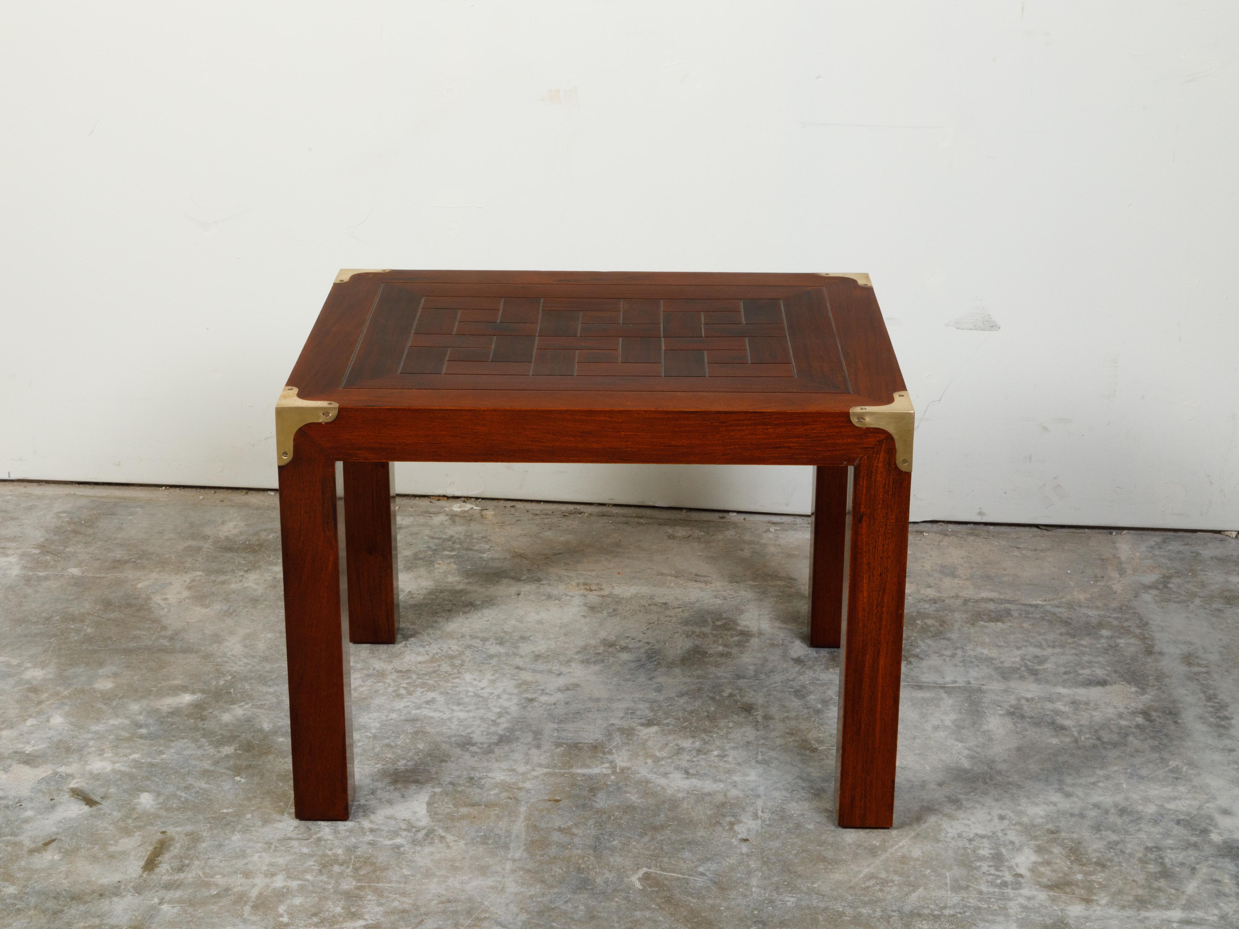 An English Campaign style walnut side table from the mid 20th century, with parquet style top, brass accents and straight legs. Created in England during the midcentury period, this walnut Campaign side table features an interesting rectangular top