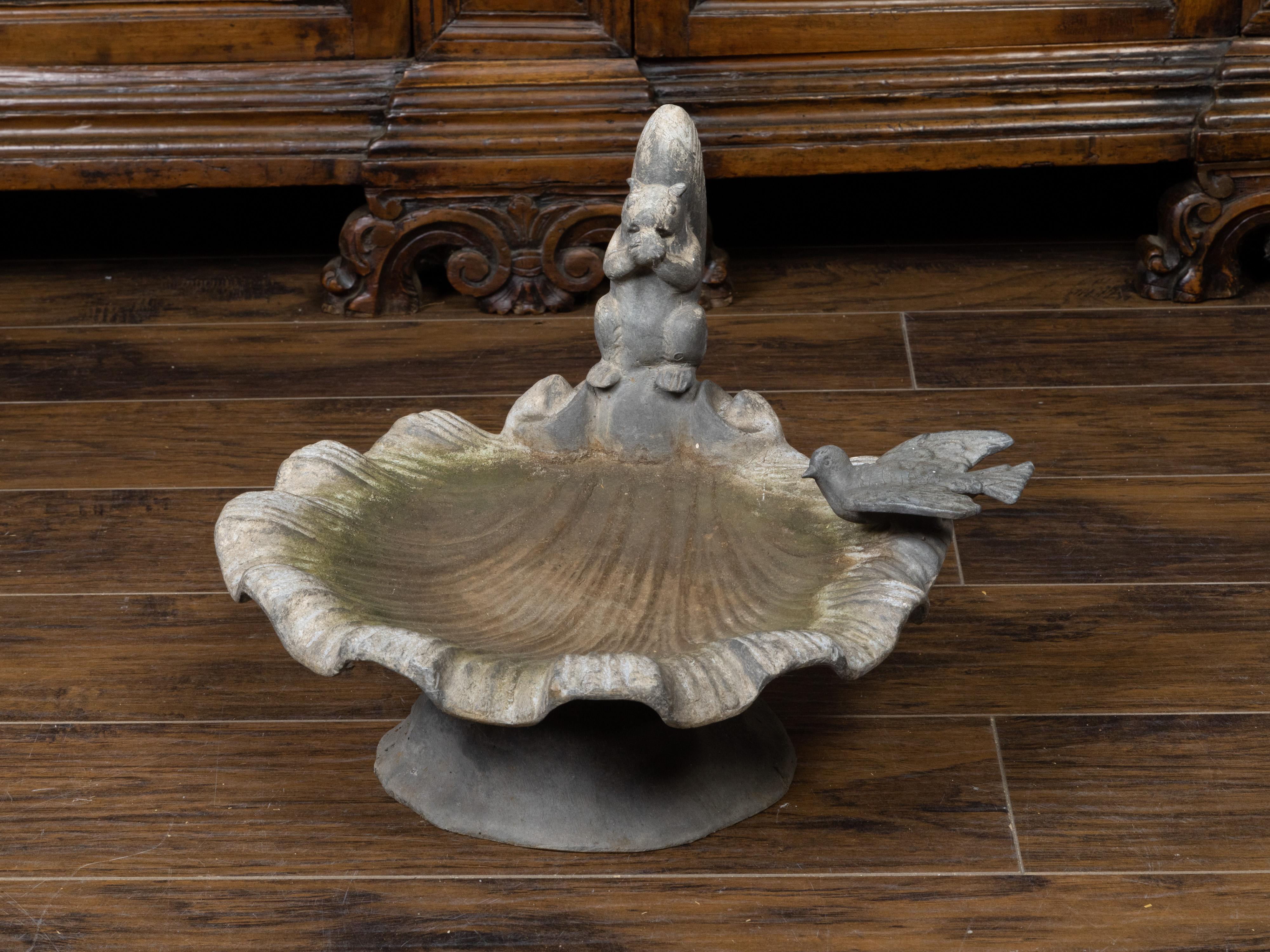 An English lead bird bath from the mid 20th century, with squirrel and bird sitting on a shell. Created in England during the midcentury period, this lead bird bath features a scalloped shell on base, on which a squirrel and a bird are resting. The