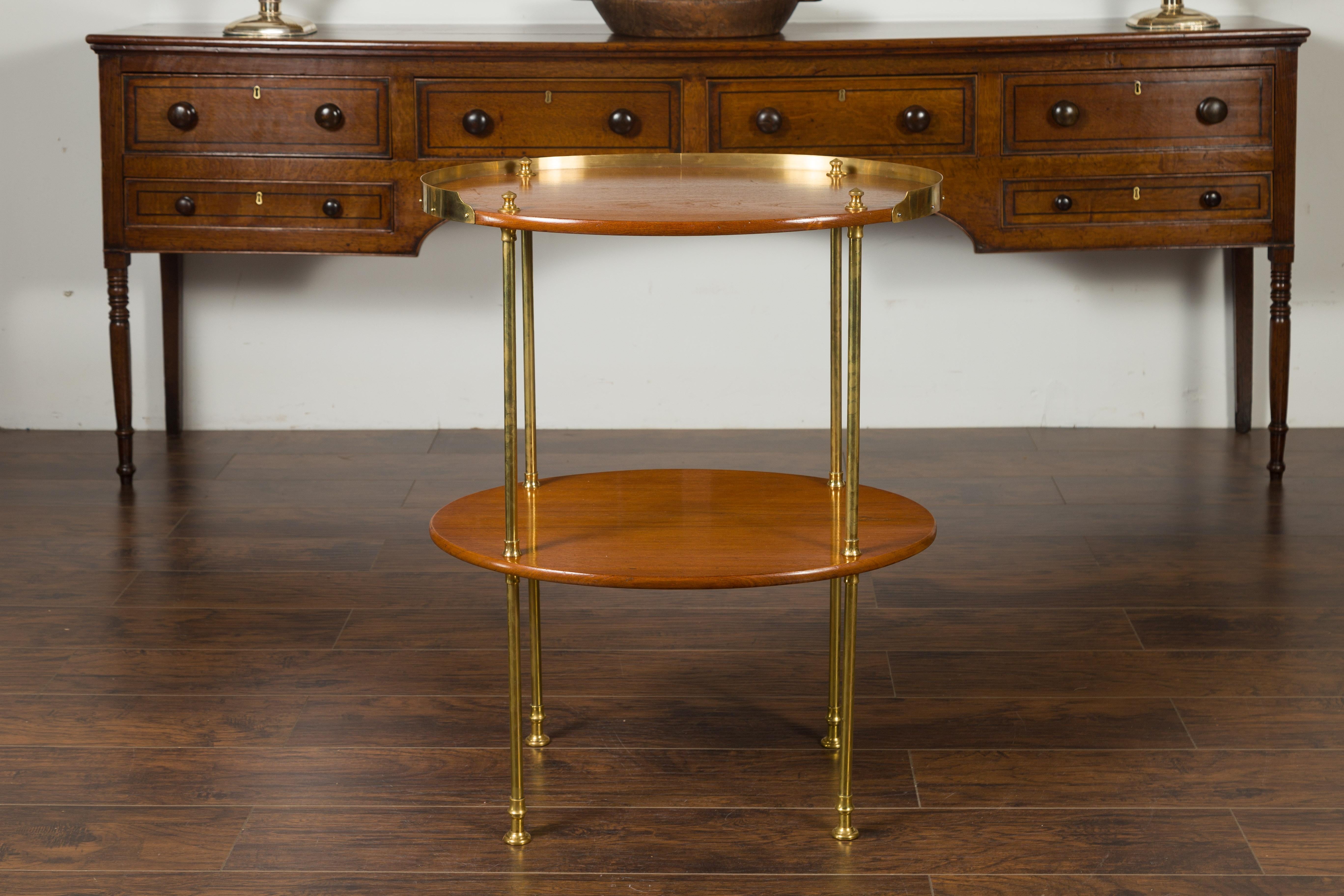 Une table ovale à étages en acajou anglais du milieu du 20e siècle, avec des accents en laiton. Née en Angleterre au milieu du siècle dernier, cette table à deux niveaux présente un plateau ovale entouré d'une galerie en laiton aux trois quarts,