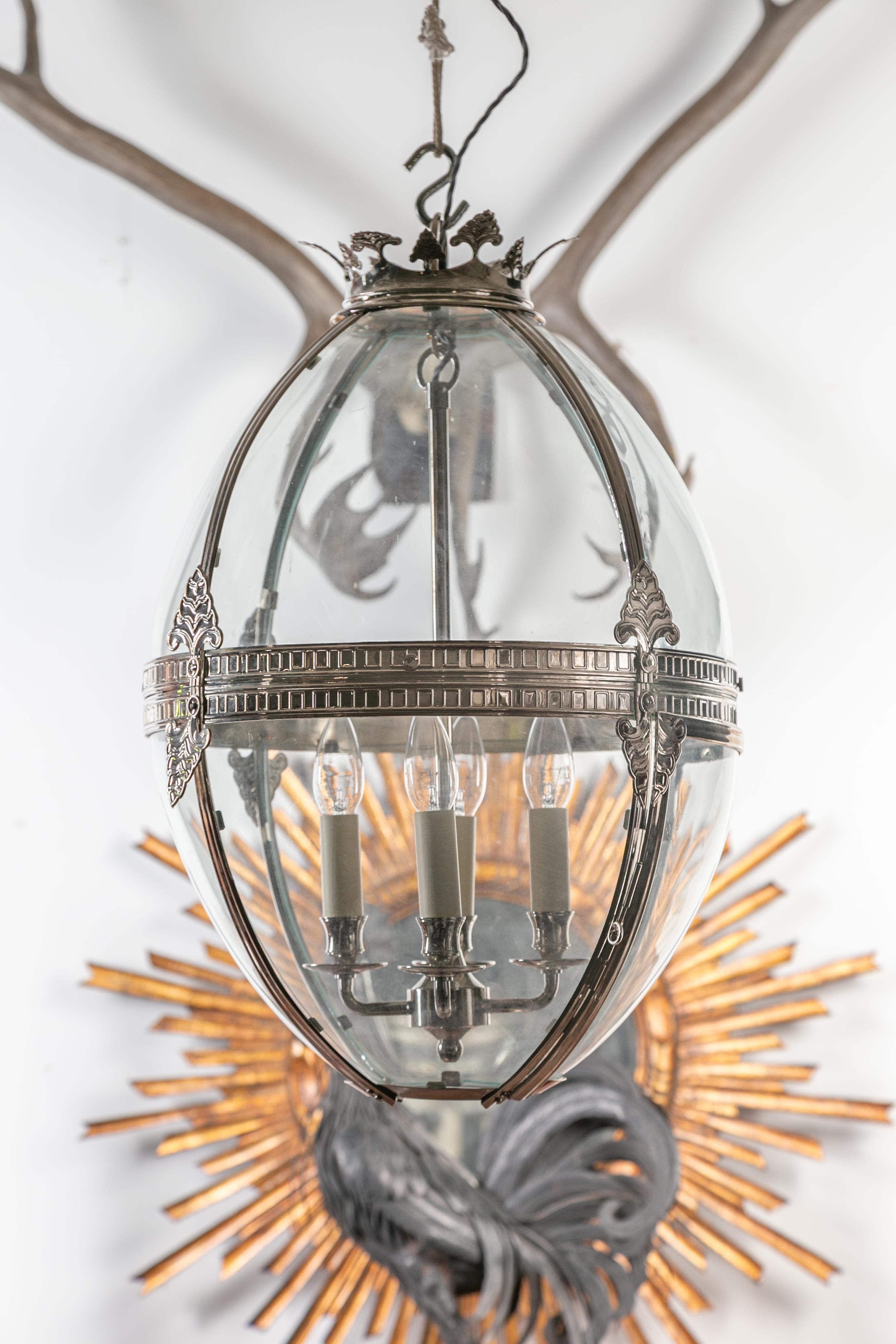 An English vintage four-light ovoid nickel light fixture from the mid-20th century, with palmette motifs and glass panels. Created in England during the midcentury period, this nickel light fixture captures our attention with its ovoid silhouette,