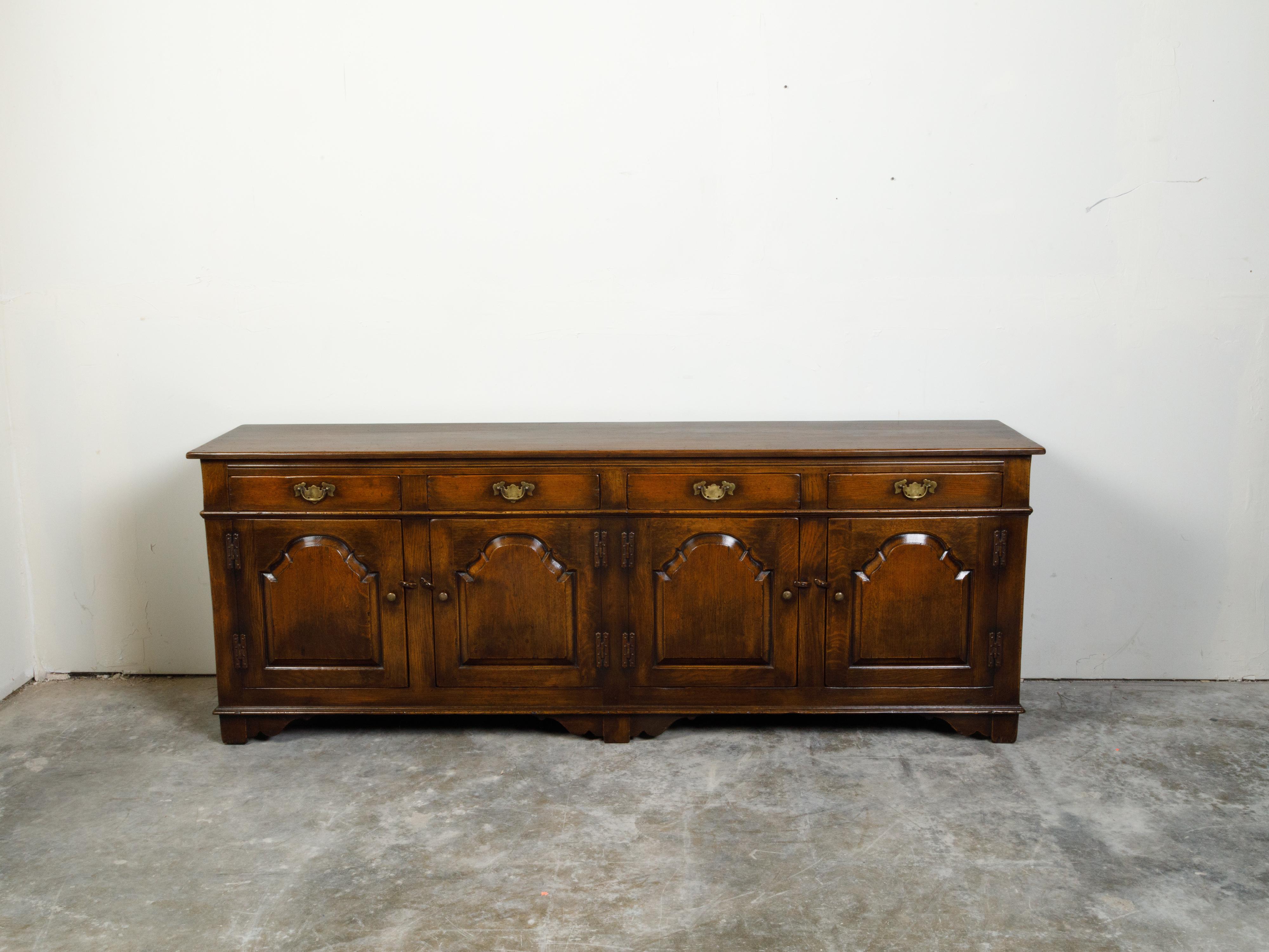 An English oak enfilade from the mid 20th century, with four drawers over four doors. Created in England during the midcentury period, this oak enfilade features a rectangular top sitting above four drawers fitted with brass Chippendale style