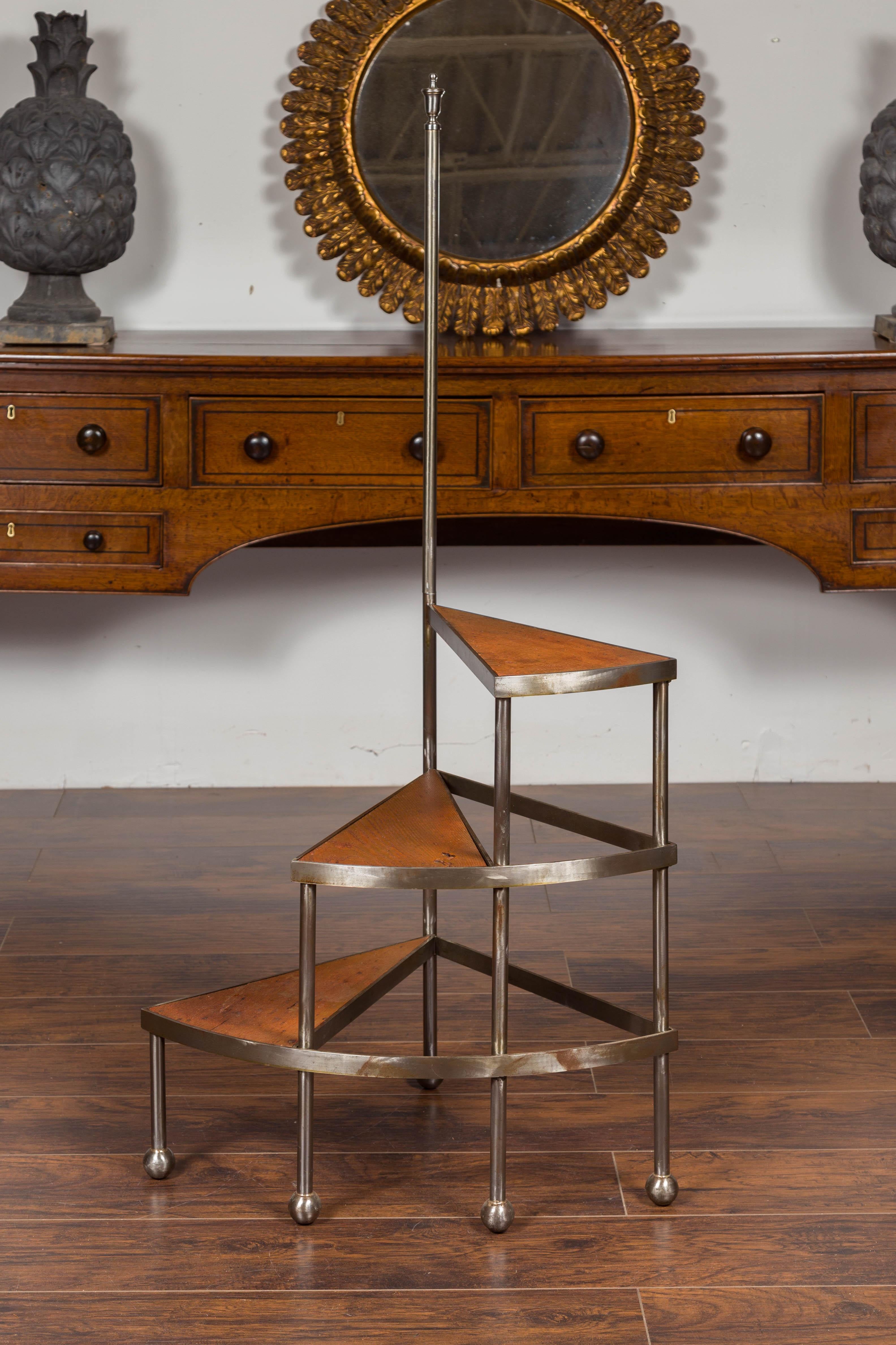 English steel and oak library steps from the mid-20th century, with spiral design and ball feet. Born in England during the midcentury period, these library steps feature a central steel pole topped with an urn-shaped finial, connected to three oak
