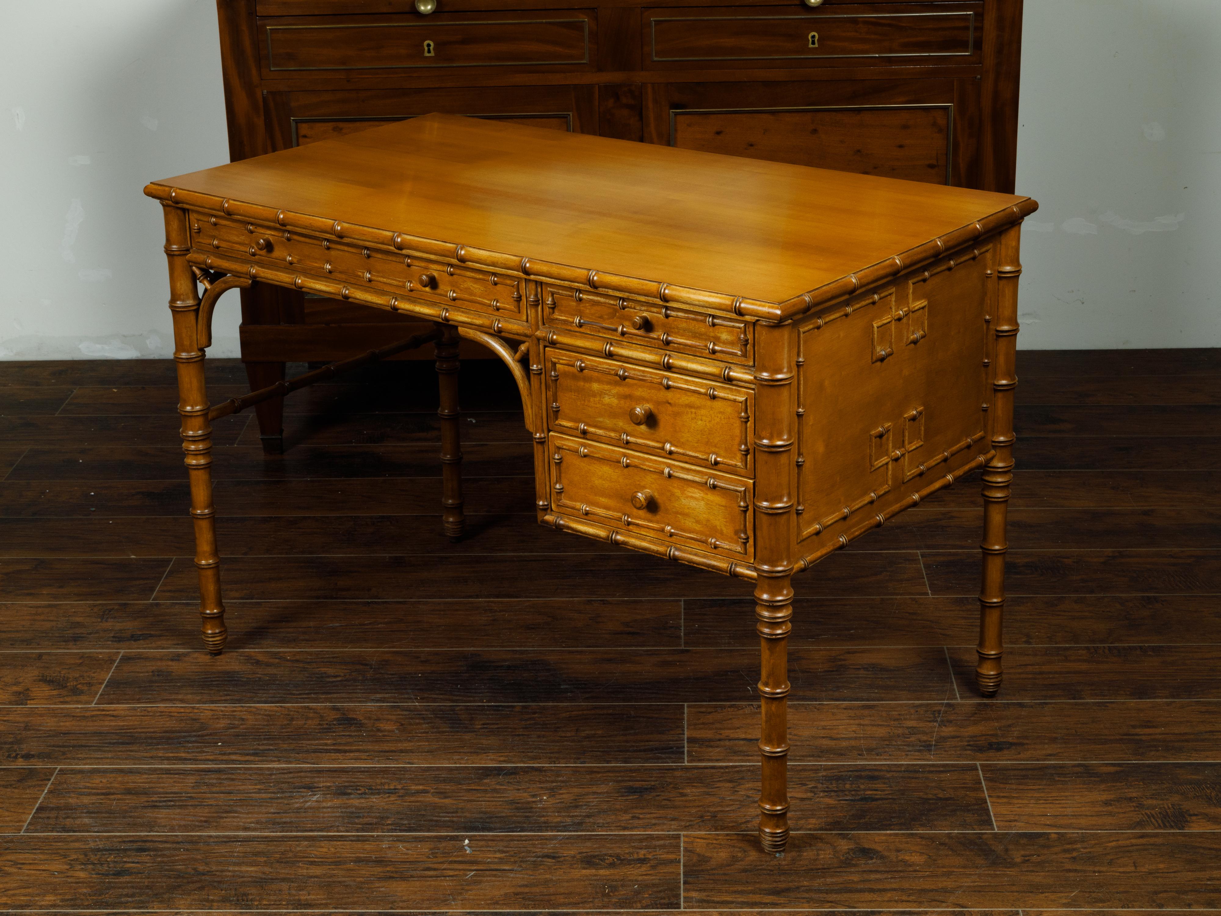 An English faux bamboo walnut desk from the mid 20th century with four drawers and warm patina. Created in England during the Midcentury period, this walnut faux bamboo desk features a rectangular top sitting above an elegant façade. A long and