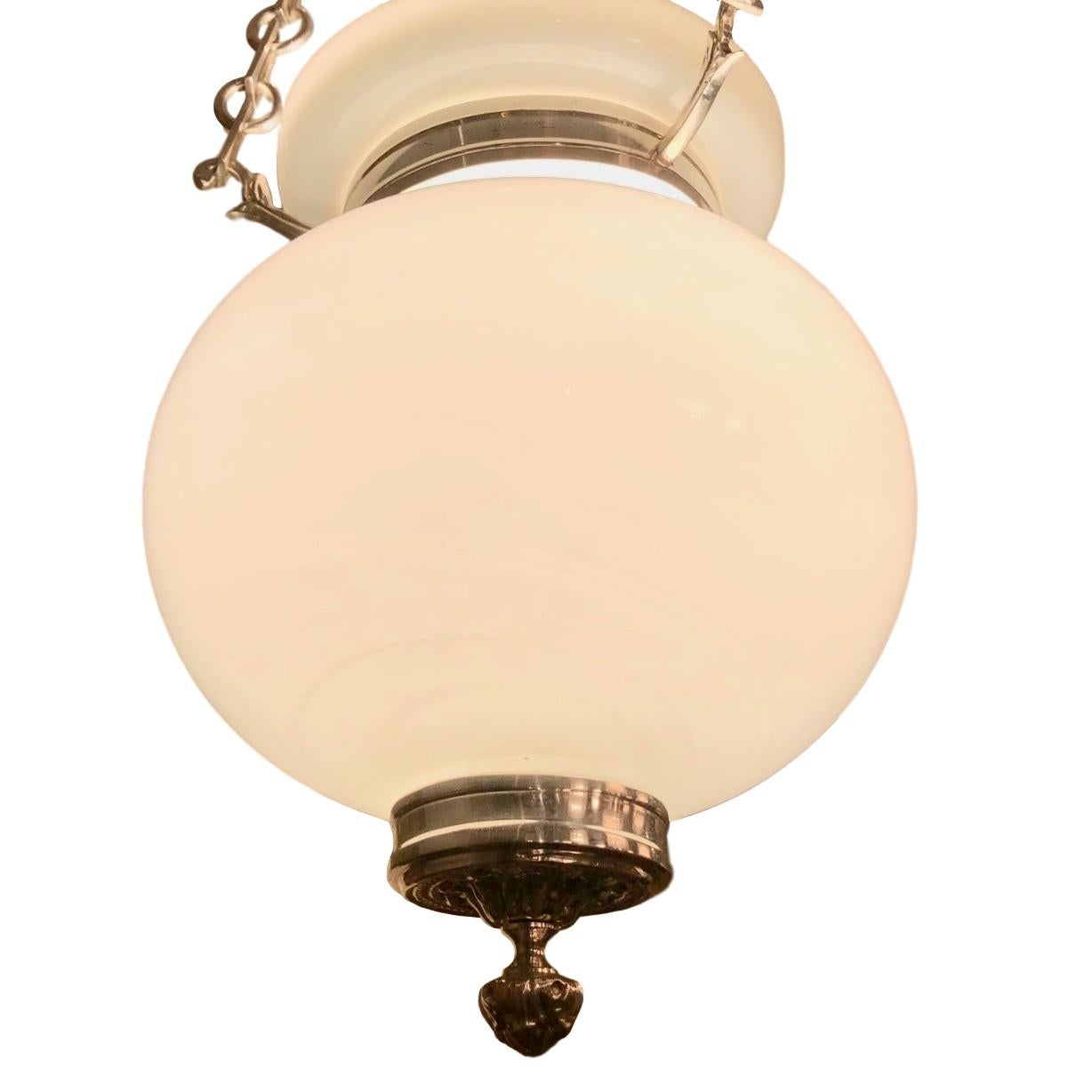 A circa 1920s English milk glass pendant lantern with three interior candelabra lights.

Measurements:
Current drop (height can be adjusted): 27
