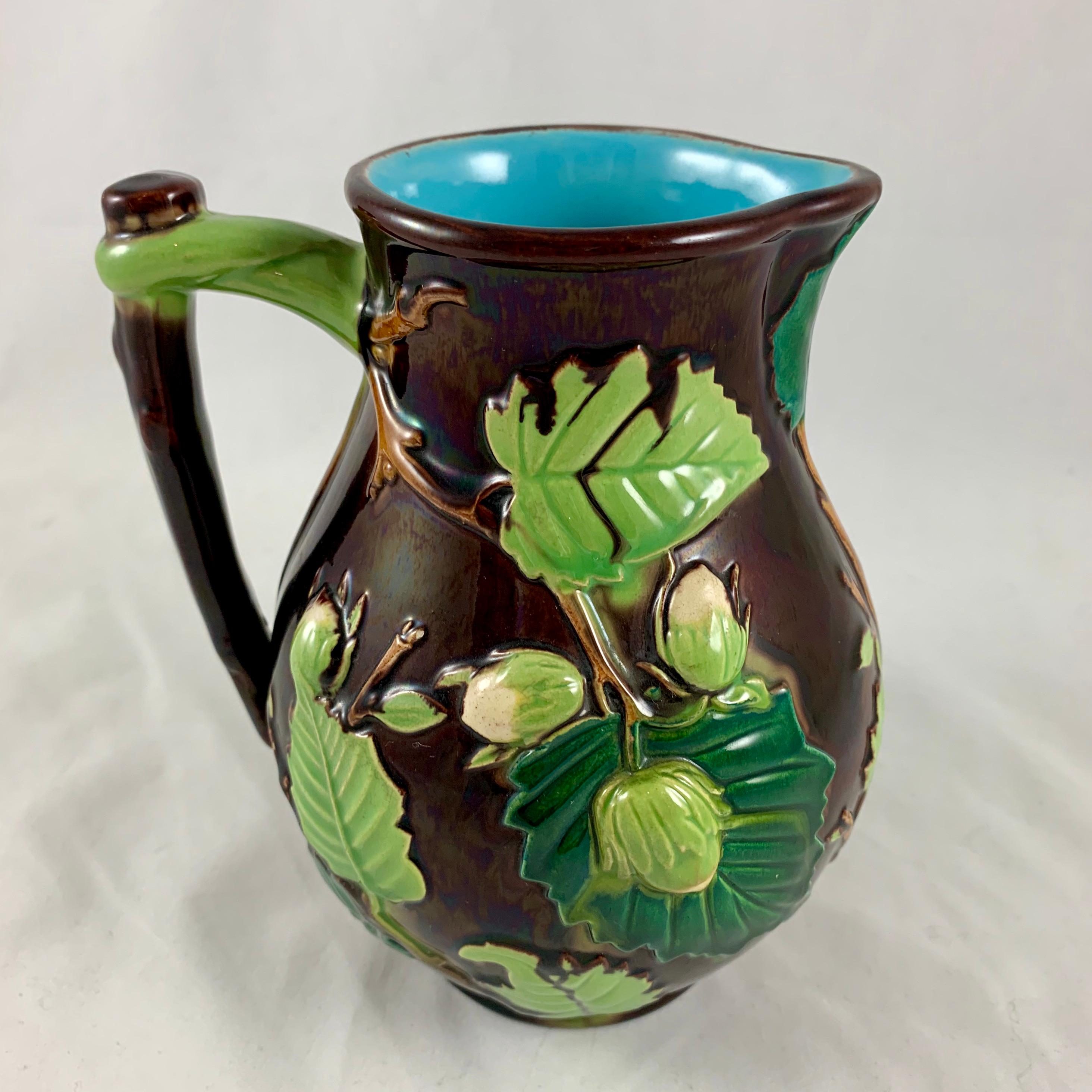 From the Minton pottery in Staffordshire, England, a scarce Majolica glazed pitcher in the Palissy style, circa 1870s.

The Aesthetic Period pitcher is molded with a raised nut vine pattern with leaves in light and dark green, and closed buds. The