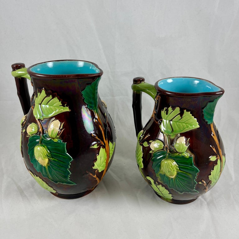 Attributed to Minton pottery in Staffordshire, England, a scarce sized set of majolica glazed pitchers in the Palissy style, circa 1870s.

The Aesthetic Period pitchers are molded with a raised nut vine pattern with leaves in light and dark green,
