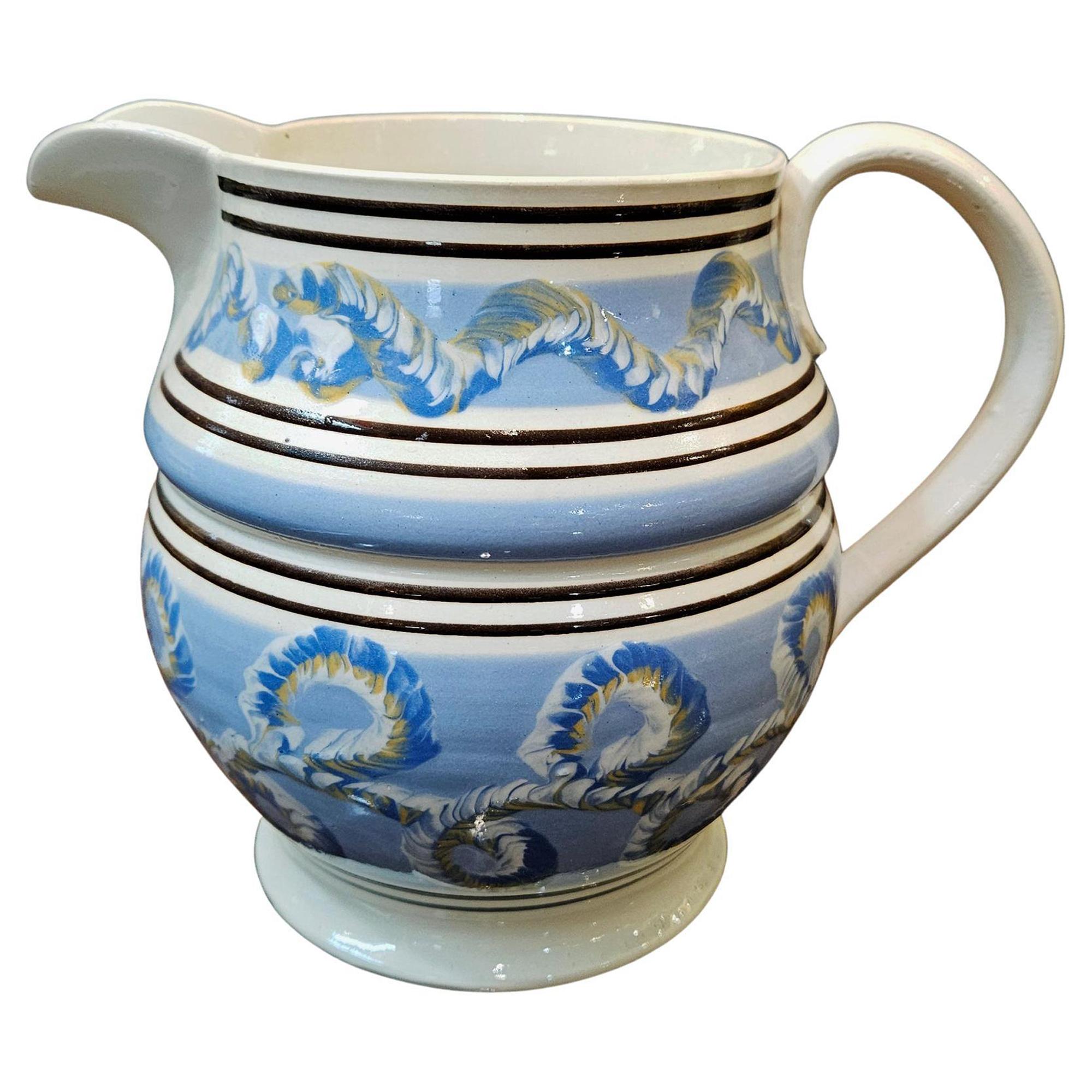 Jarra inglesa de cerámica mocha Pearlware Earthworm,
Circa 1800-20

La jarra de moca perlada tiene tres bandas de engobe azul y cuatro de fondo blanco con dos líneas rojo-marrón.  El slip azul está decorado con un diseño tricolor de lombriz de