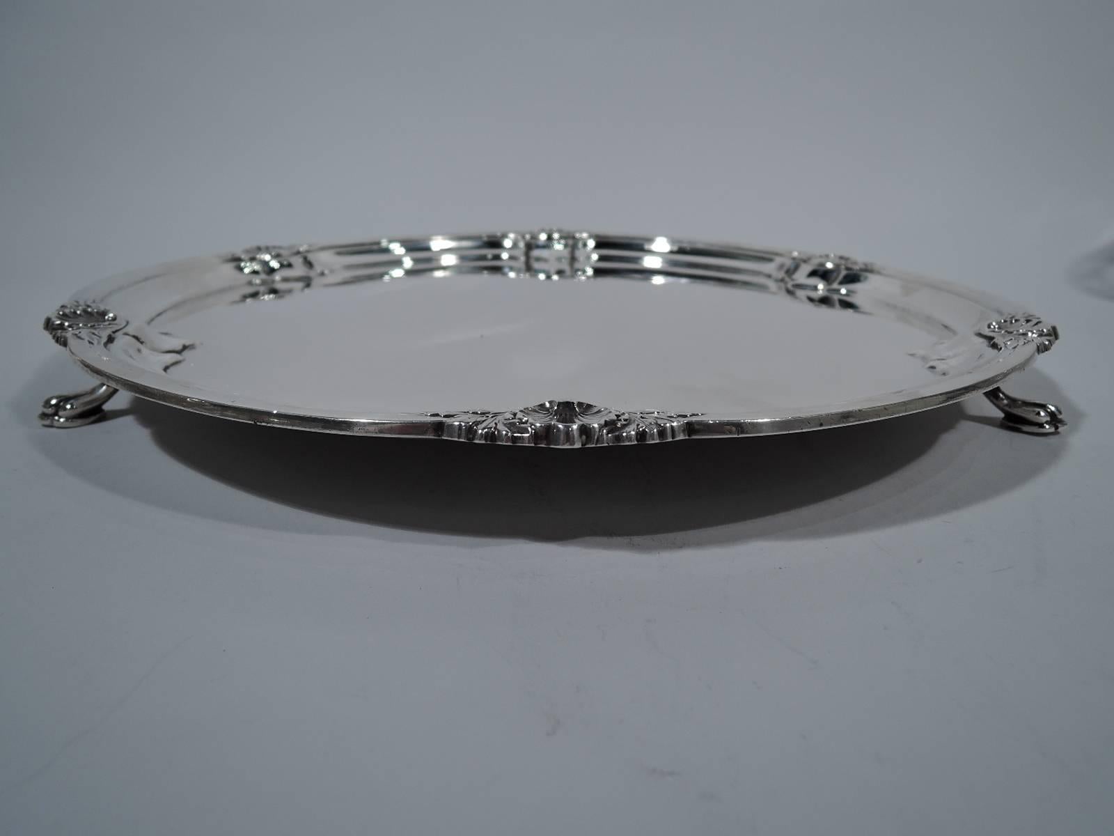 George V sterling silver salver. Made by Cooper Bros & Sons in Sheffield in 1927. Lobed well. Rim molded with applied shells and leaves. Rests on three paw supports. An elegant updating of Georgian motifs. Hallmarked. Weight: 41 troy ounces.