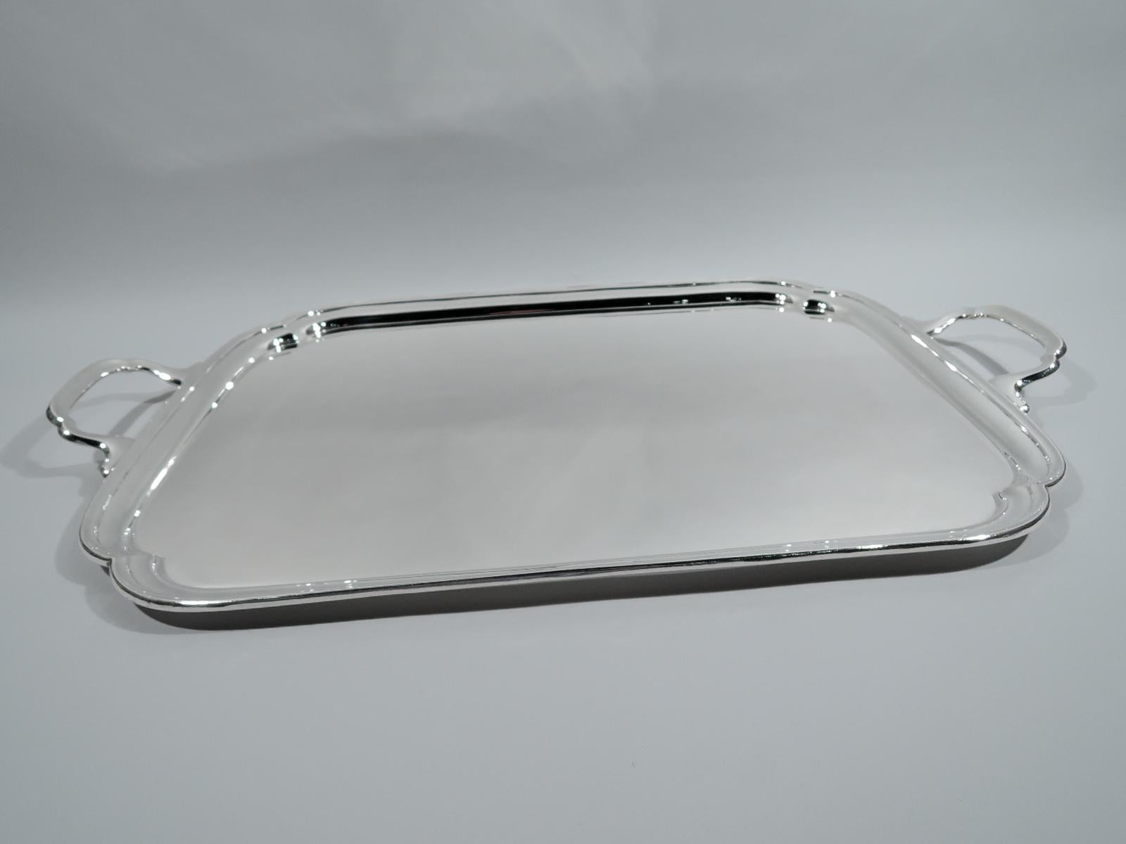 George VI sterling silver tea tray. Made by Edward Viner in Sheffield in 1951. Rectangular with double scalloped corners, molded rim, and shaped bracket handles. Georgian inspiration for traditional and Modern tables. Fully marked. 

Overall