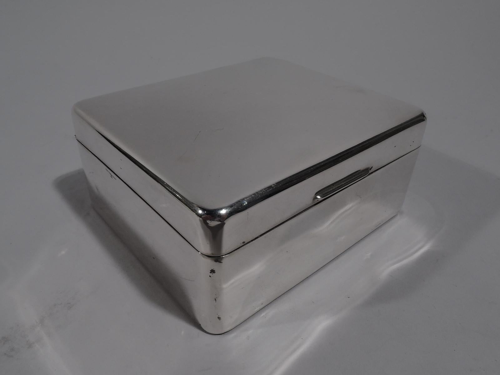 Smart and small sterling silver box. Made by Adie Bros in Birmingham in 1956. Rectangular with curved corners. Cover flat, hinged, and tabbed. Interior cedar lined. Underside leather lined. Fully marked. Gross weight: 9.5 troy ounces.