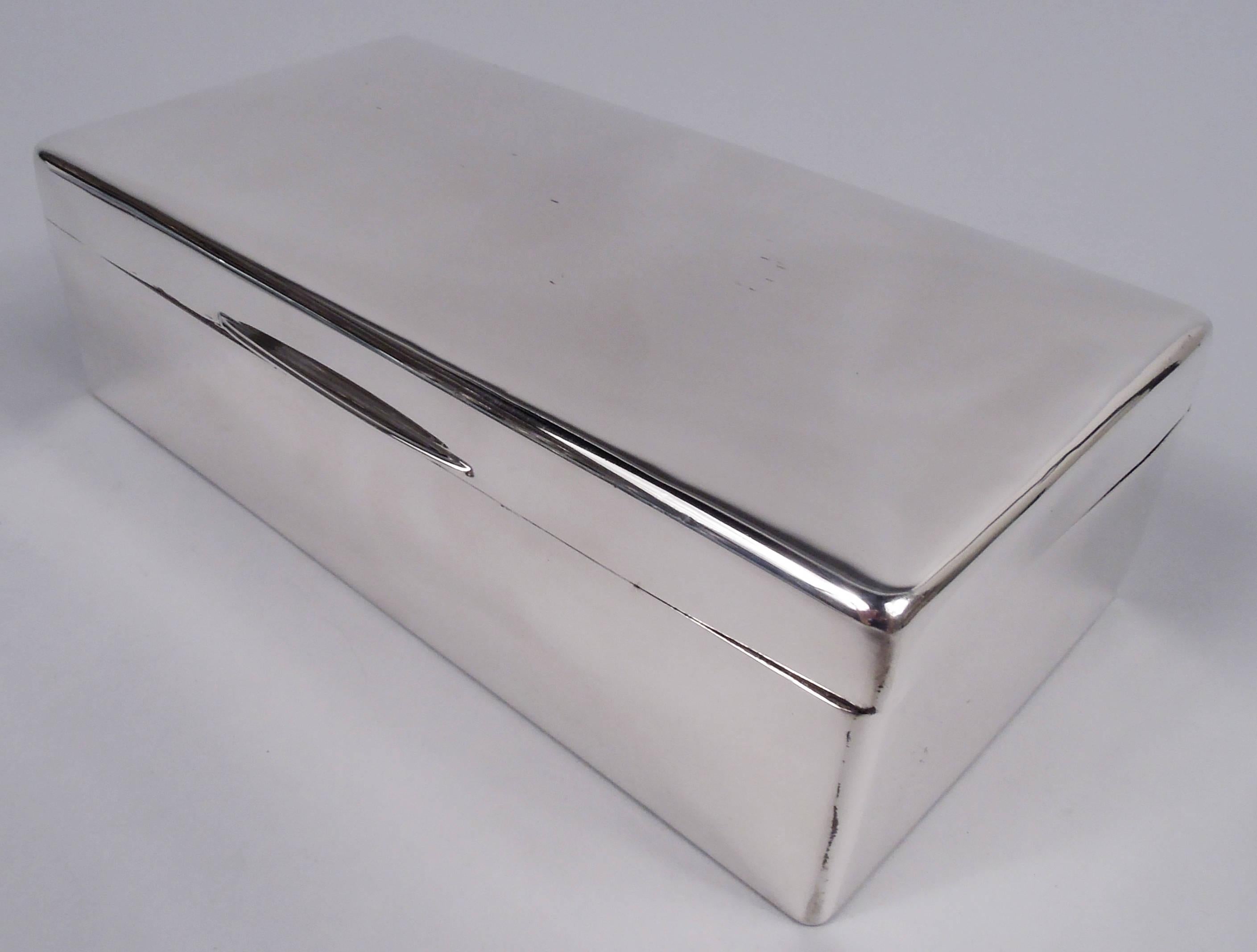 George VI sterling silver box. Made by WH Manton in Birmingham in 1938. Rectangular with curved corners. Cover hinged with gently curved top and tapering tab. Cedar-lined and partitioned interior; wood lined underside. Fully marked. Gross weight: 18