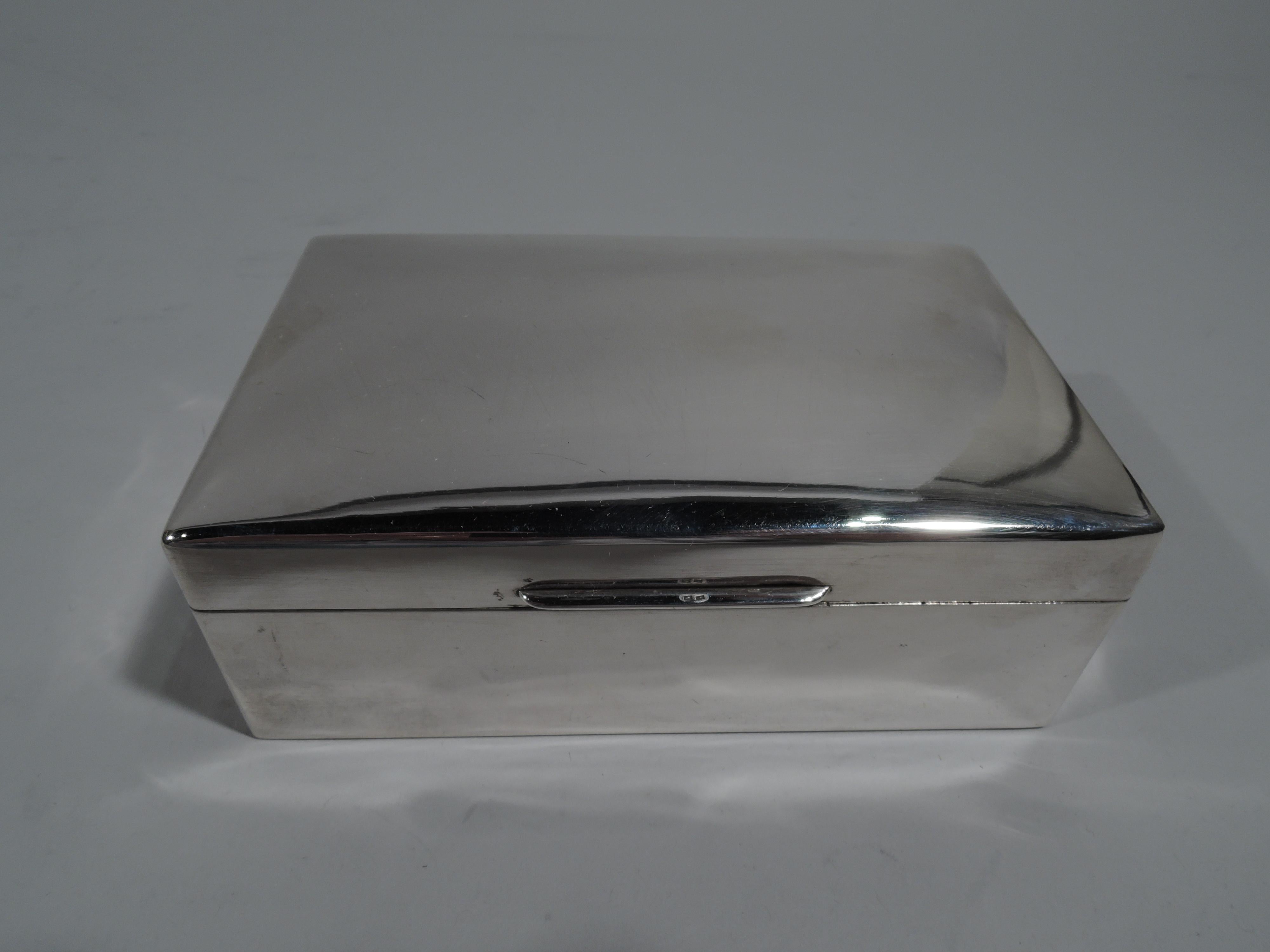 George V sterling silver box. Made by Richard Comyns in London in 1929. Rectangular with straight sides. Cover gently curved and hinged with linear tab. Interior cedar-lined and partitioned. Underside leather-lined. Fully marked. Gross weight: 15