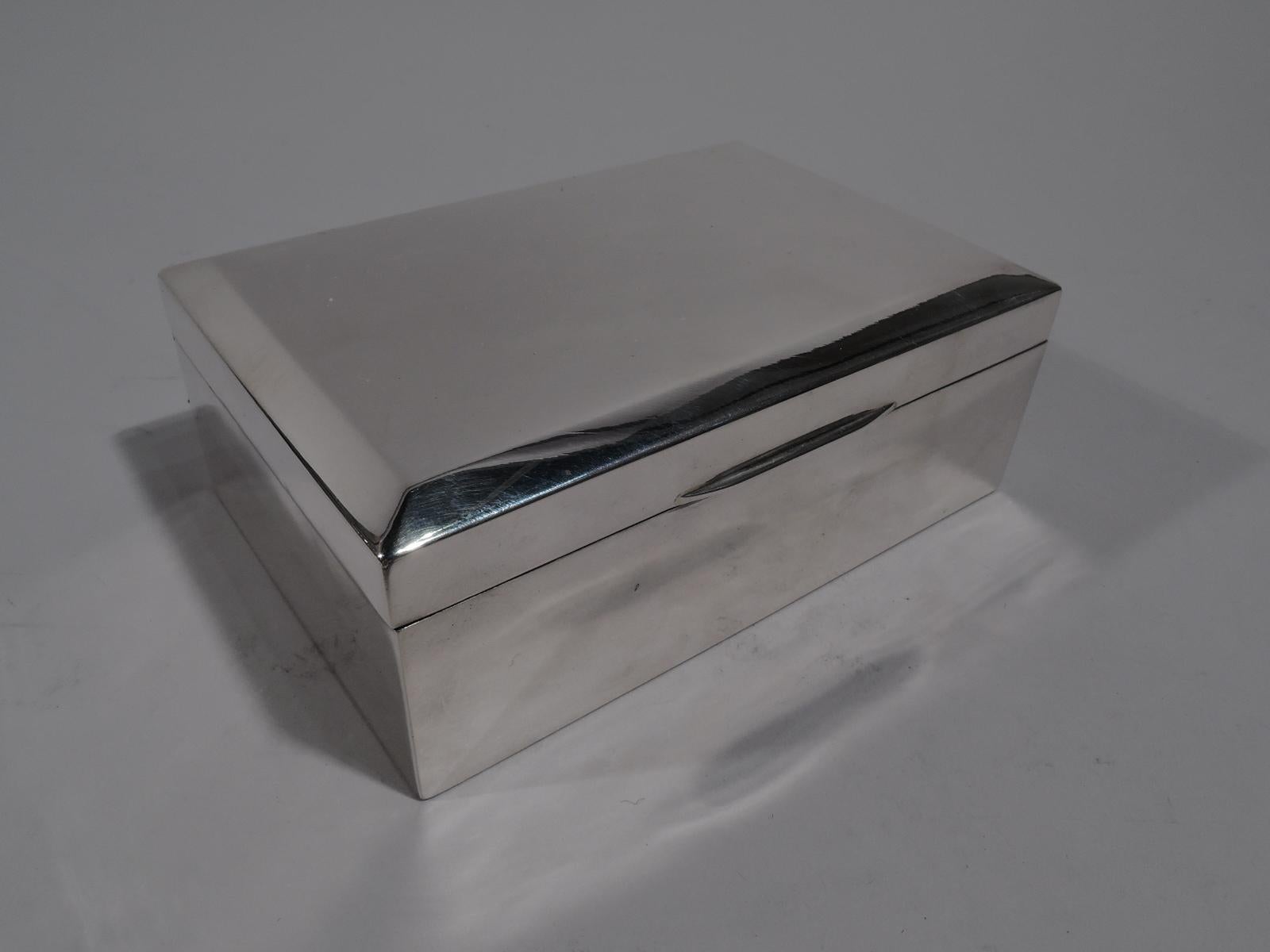 George V sterling silver box. Made by Henry James Cooper & Co., Ltd in Birmingham in 1926. Rectangular with straight sides. Cover hinged and tabbed with flat and canted top. Box and cover interior cedar lined and partitioned. Underside leather