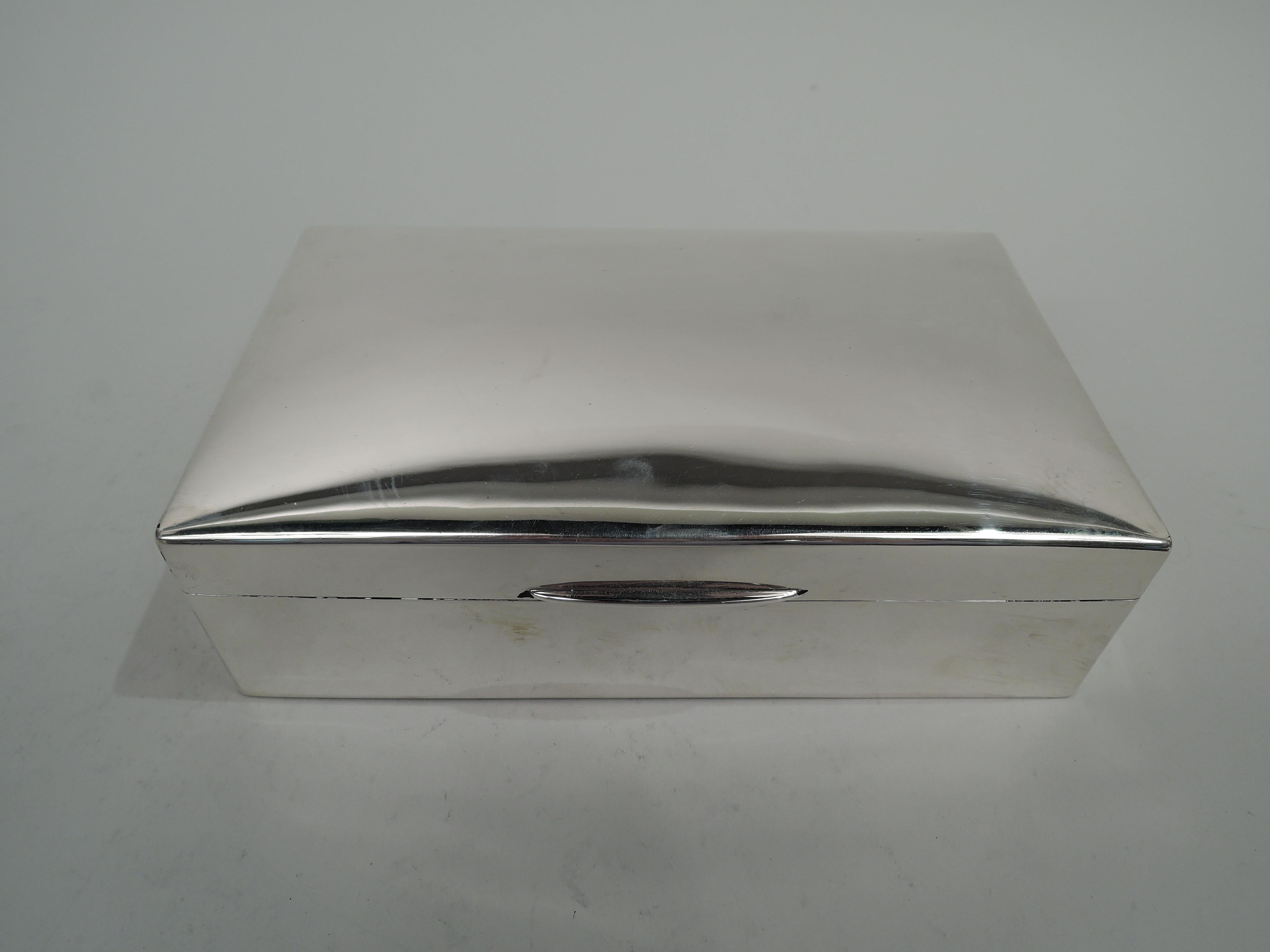 George V sterling silver box. Made by Deakin & Francis in Birmingham in 1923. Rectangular with straight sides and curved corners. Cover hinged with gently curved top and tapering tab. Box interior cedar lined and partitioned. Cover interior gilt