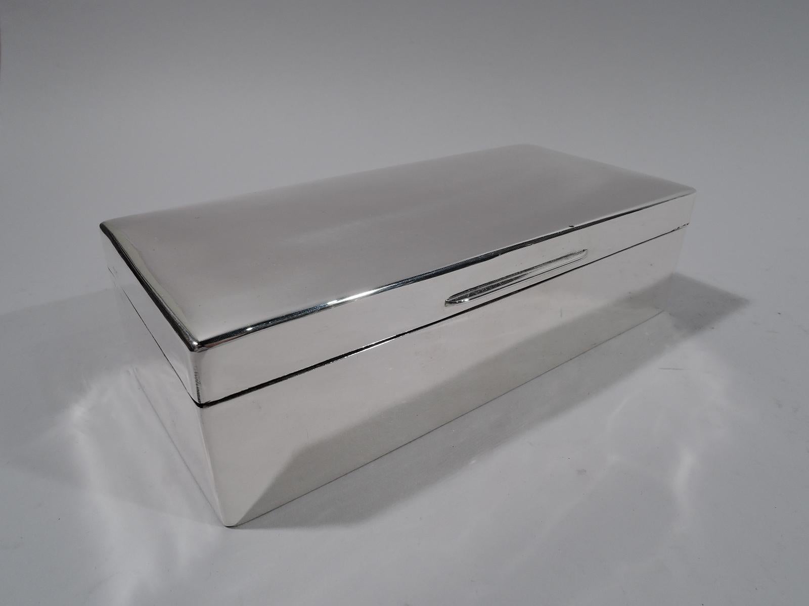 George V sterling silver desk box. Made by Charles Boyton & Son in London in 1924. Rectangular with straight sides. Cover hinged and gently curved with linear tab. Box and cover interior cedar lined and partitioned. Underside leather lined. Fully