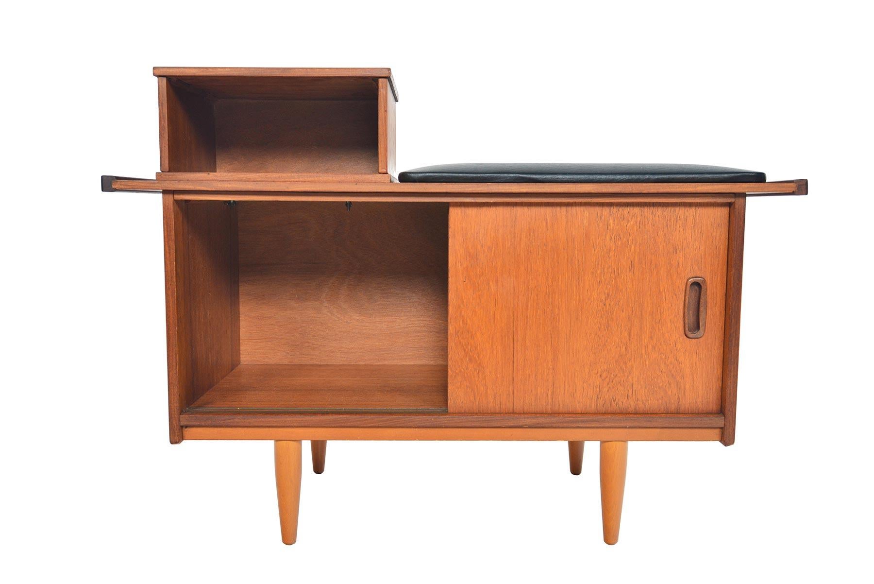 This English Mid-Century Modern telephone bench by Jentique is crafted in teak to provide a compact design for seating and storage. Perfect for any entryway, this time capsule design offers a vinyl covered cushions. A wonderful storage piece, this