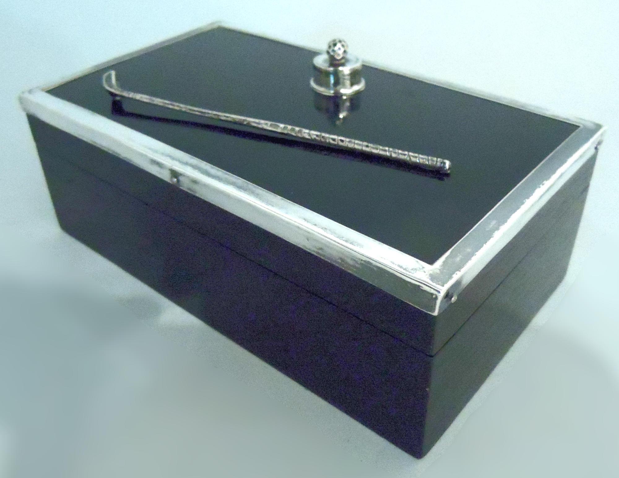 Scatola moderna inglese in legno ebanizzato con montature in argento, 1927. Rettangolare con lati dritti; coperchio incernierato con parte superiore piatta e bordo argentato. Sulla parte superiore sono montate una mazza da golf e una pallina sul