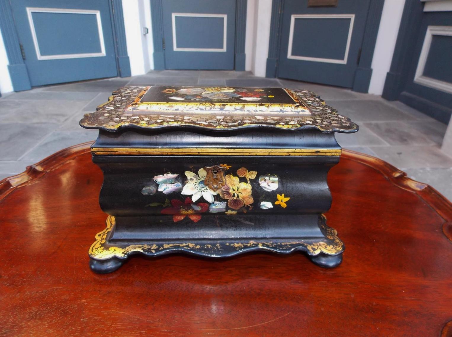 English black lacquered Papier mache and mother of pearl inlaid hinged tea caddy with scalloped edge carvings, two lidded foil lined interior compartments, and resting on the original bun feet. Early 19th century.