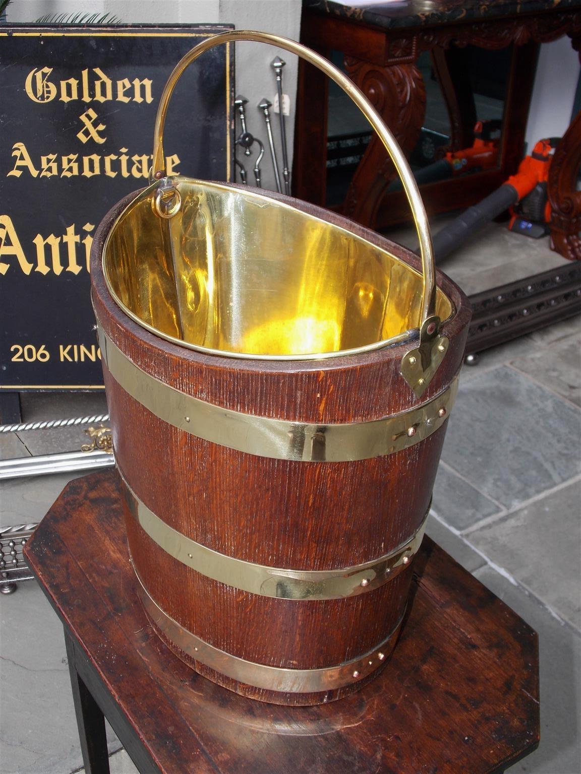 English navette form oak brass banded peat bucket with the original side mounted brass handle and removable interior brass liner. Early 19th century.