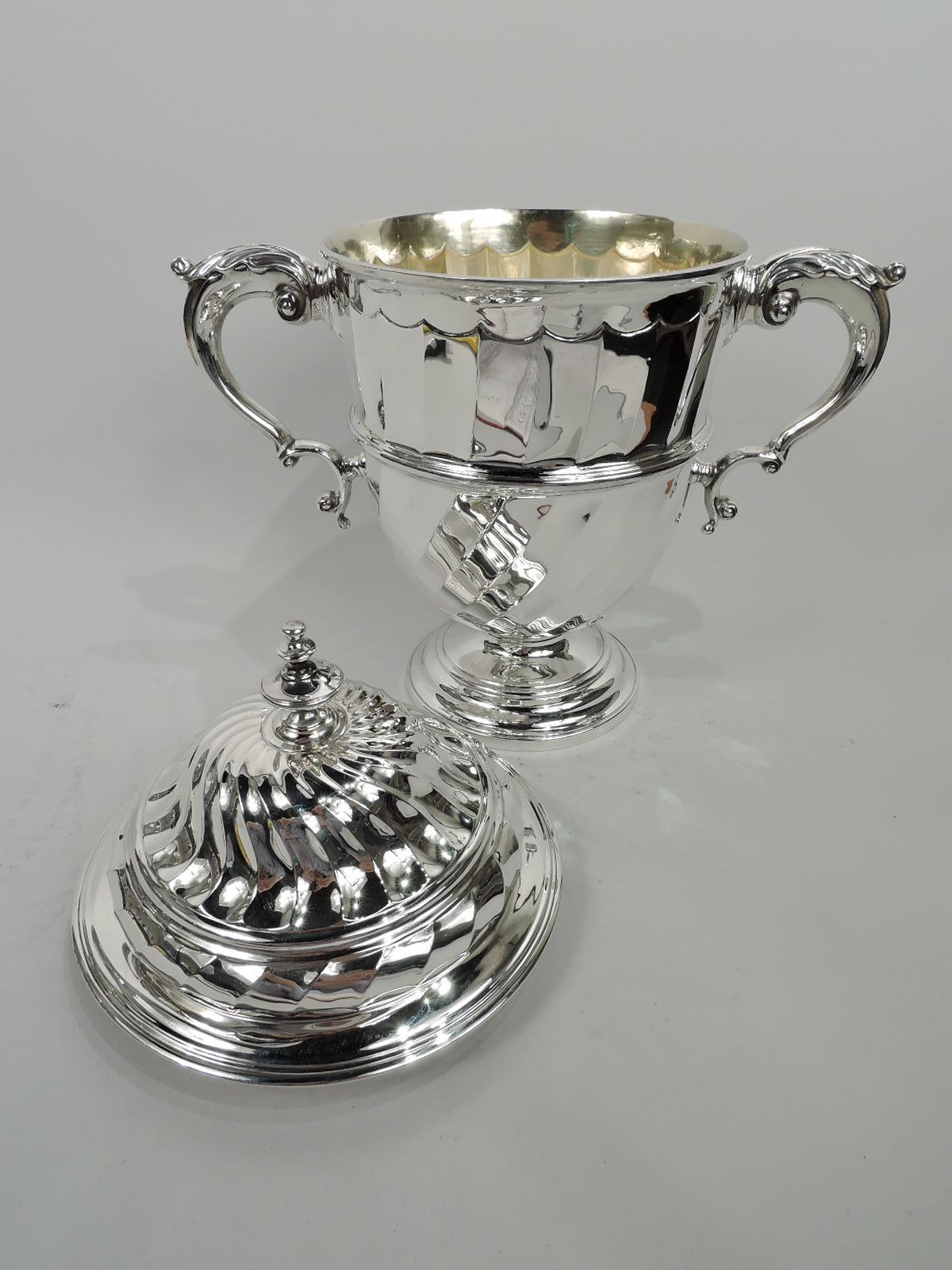 Elizabeth II sterling silver covered urn. Made by Solomon Joel Phillips in London 1959. Traditional Neoclassical girdled urn on stepped and domed foot with leaf-capped s-scroll side handles. Cover double-domed with vasiform finial. Urn has twisted