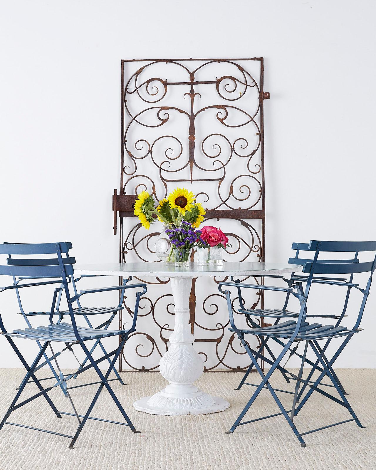 Elegant English wrought iron and cast iron patio or garden table. Features a round top inset with frosted glass supported by a scrolled wrought iron frame. The heavy pedestal base is constructed from cast iron in a baluster form. Decorated in the