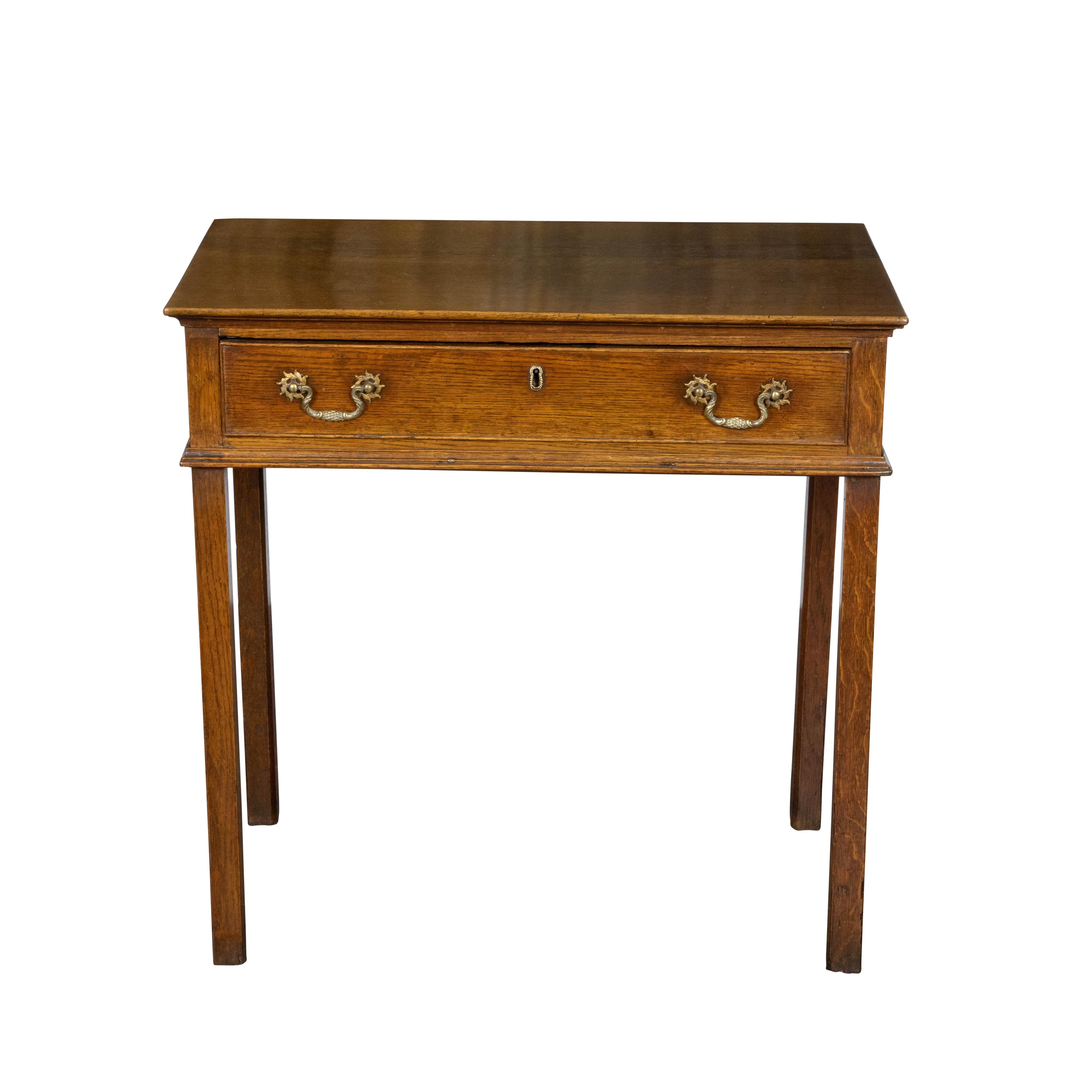 An English oak side table from the Mid-19th Century, with single drawer, brass hardware and straight legs. Created in England during the second quarter of the 19th Century, this oak side table features a rectangular top sitting above a single