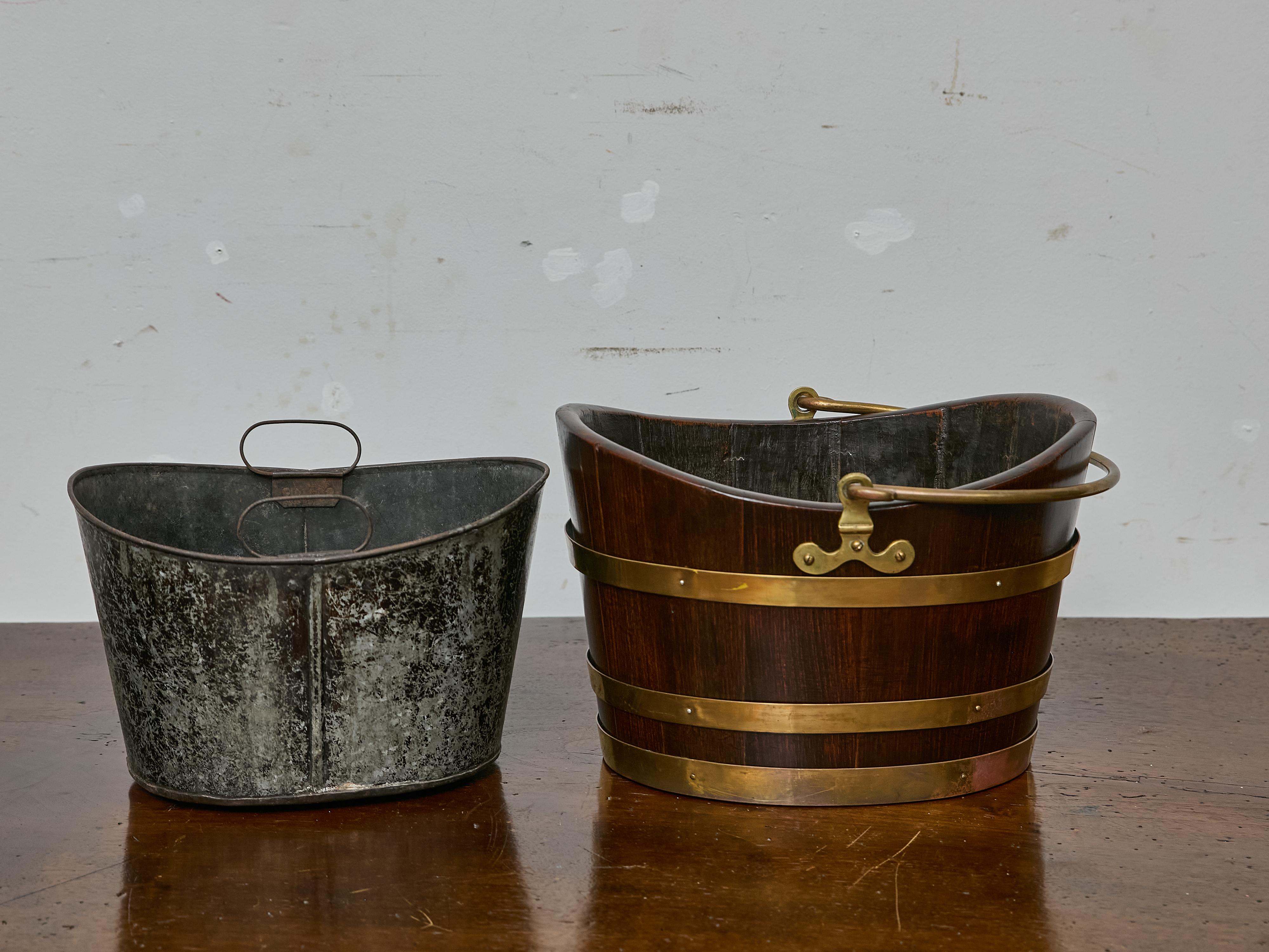 A richly patinated English oak bucket from the 19th century, featuring a warm, dark finish and original brass fittings, including three broad brass bands and a hinged bail handle with turned ends. Distinctive in both form and function, the bucket is