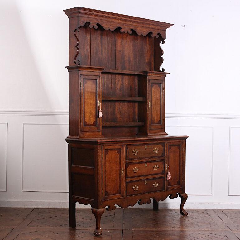 Smaller scale English oak and mahogany Welsh dresser, the base with three drawers between a pair of cabinets, the top with open shelving and two small side capboards. Shaped fretwork details to the crown and raised on carved cabriole legs. C.