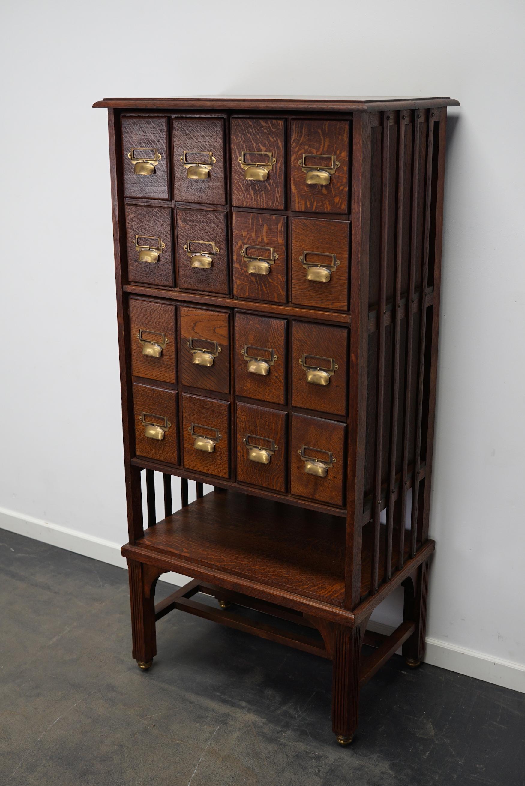 This apothecary bank of drawers / filing cabinet was designed around the turn of the century in England. The piece is made from oak with brass hardware and nice round casters.