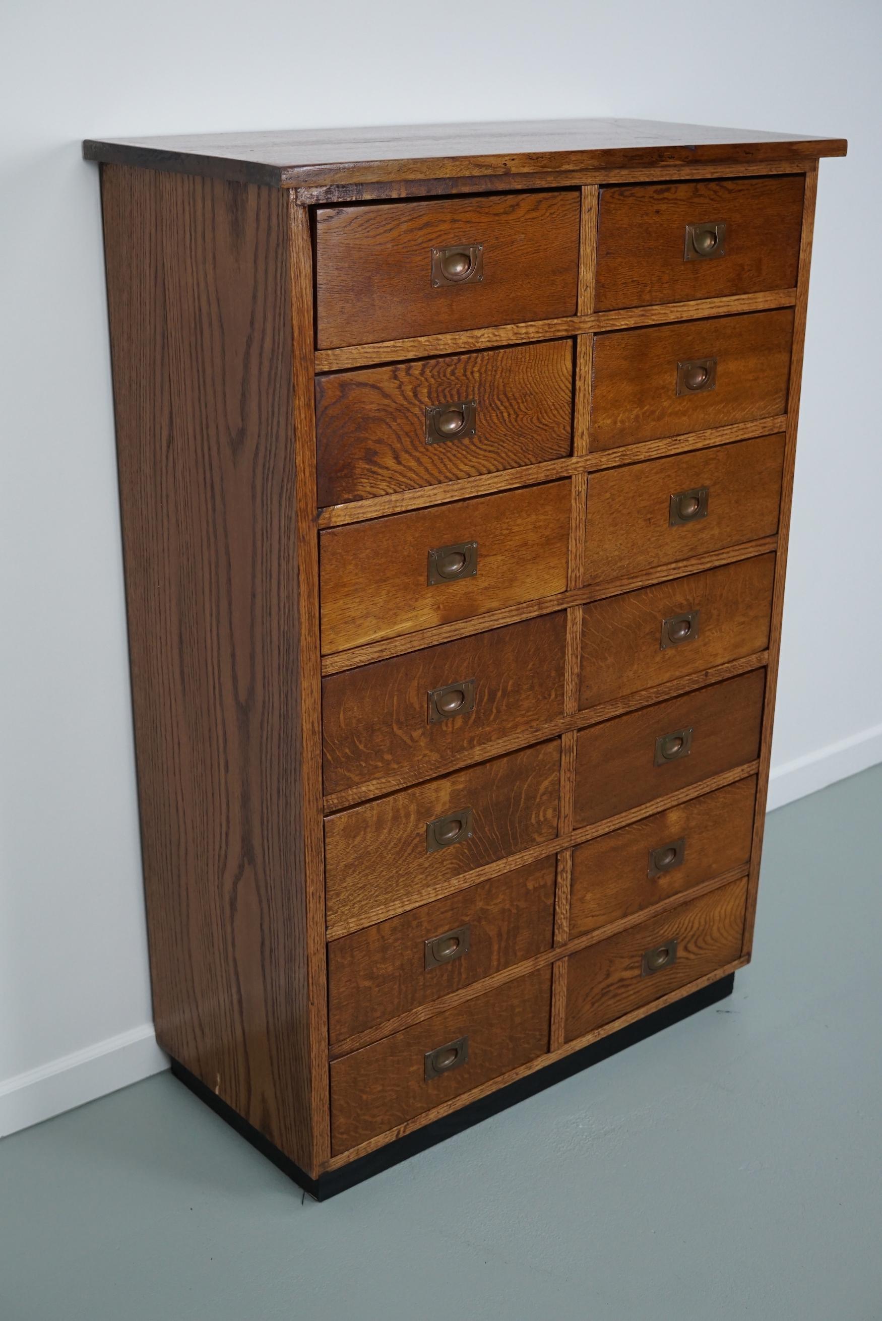 This apothecary cabinet was designed and made from oak circa 1930 in England. It features 14 drawers with brass recessed hardware. The inside of the drawers measure: DWH 30 x 31 x 11 cm.