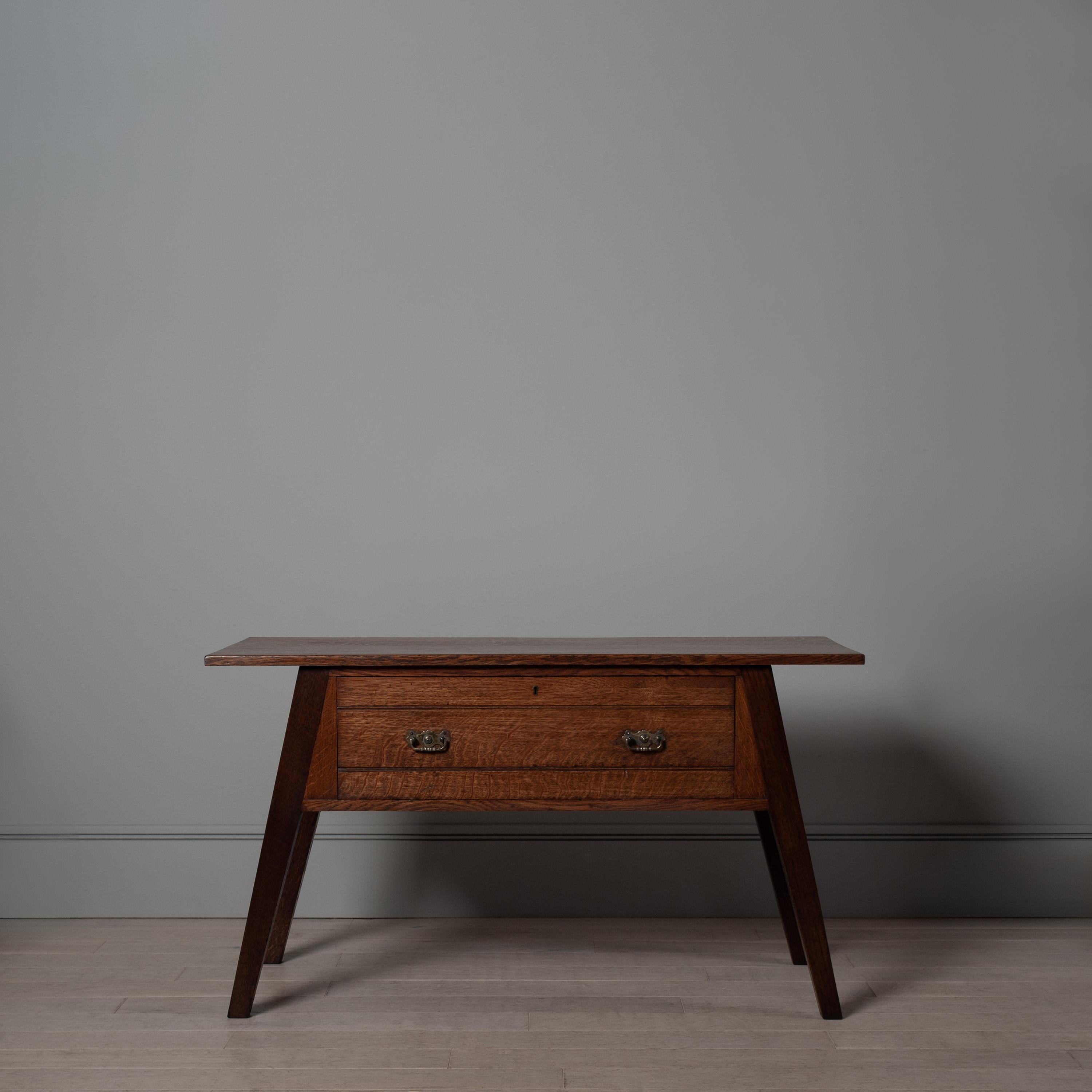Très belle et pratique table console du mouvement Arts and Crafts anglais avec un grand tiroir. Un design inhabituel et inconnu construit à partir de chêne anglais finement scié sur quartier.
Un meuble de 1900 à la fois sobre, audacieux et