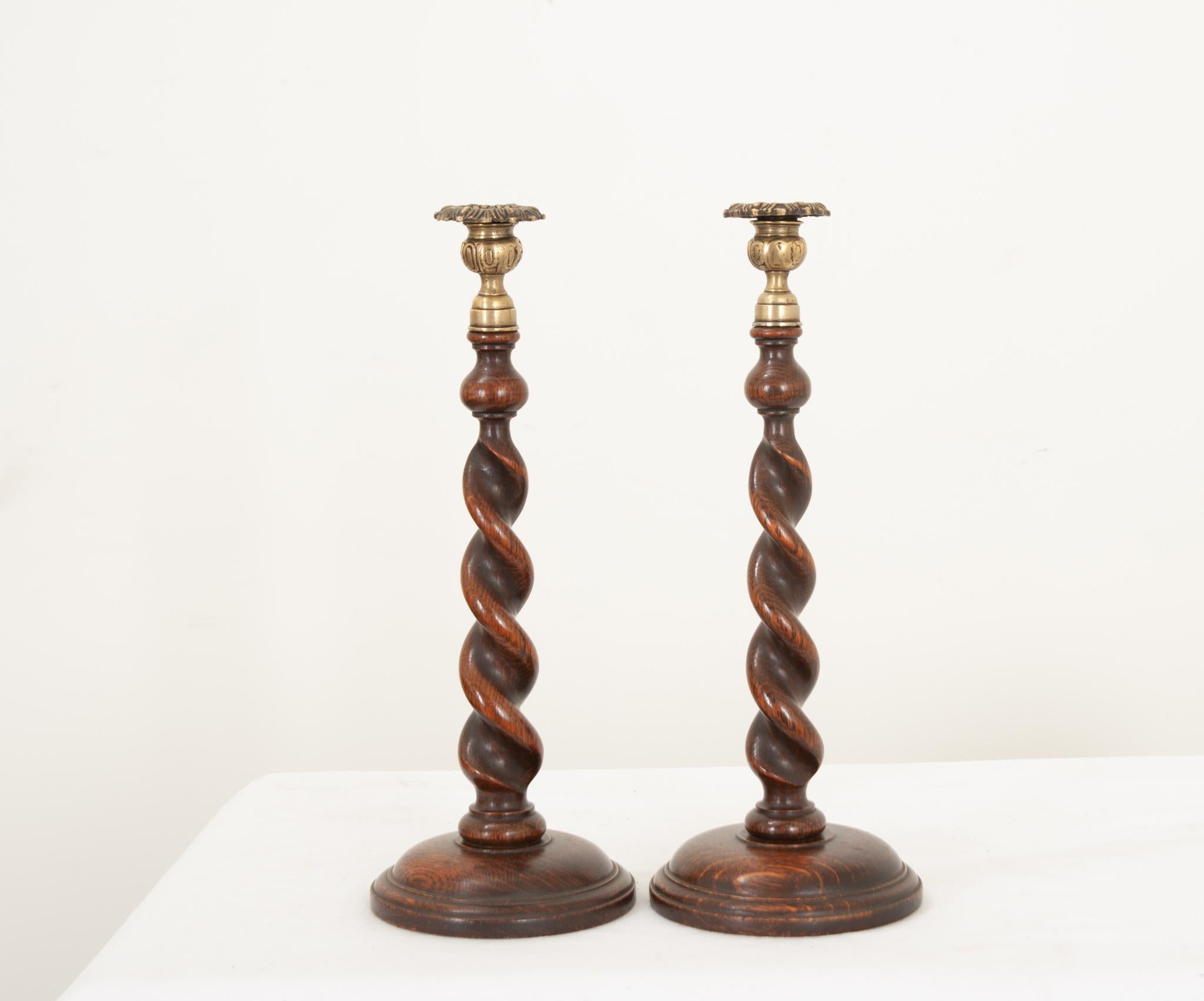 A lovely pair of oak barley twist candlestick holders from England, hand crafted during the 1880’s. The richly toned hardwood has a fantastic patina and compliments the stamped brass bobeche perfectly. A worn felt bottom prevents them from sliding