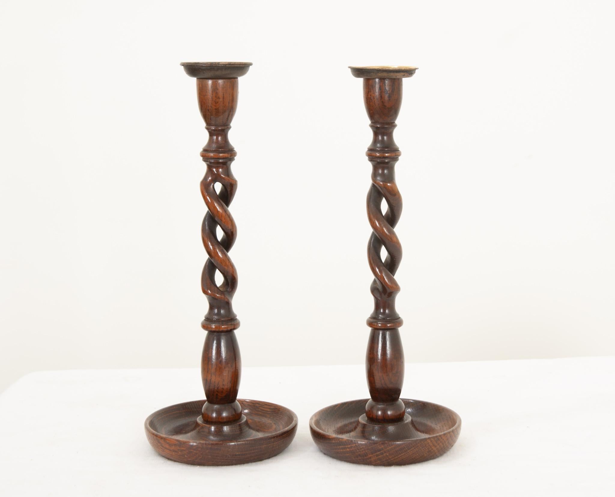 A lovely pair of oak open barley twist candlestick holders from England, hand crafted during the 1880’s. The richly toned hardwood has a fantastic patina and compliments the stamped brass bobeche perfectly. A worn felt bottom prevents them from