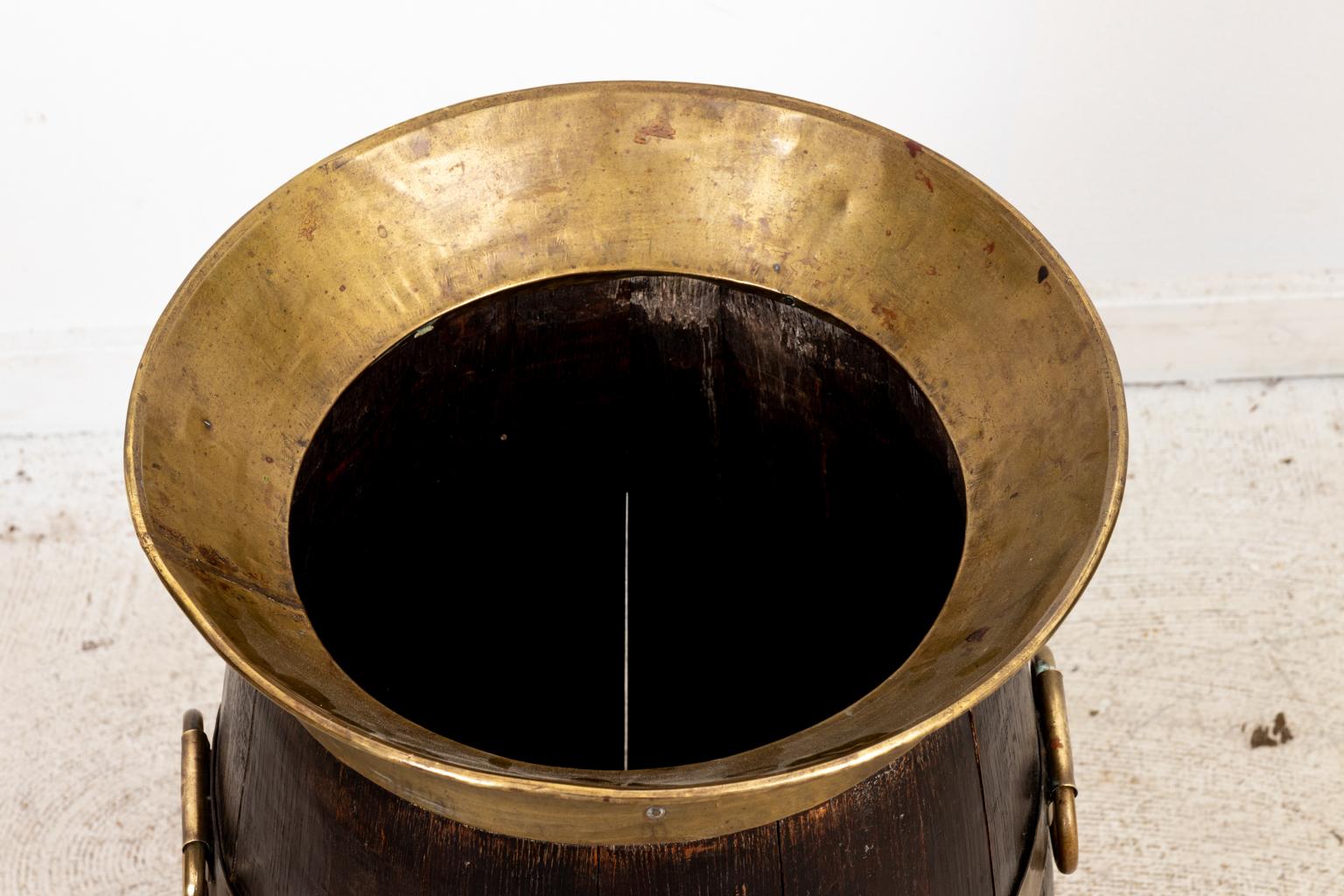 Circa 1900s large English Country style Oakwood barrel with brass banding and rings for holding umbrellas and walking sticks. The barrel is constructed with brass bands, two brass handles, and brass top rim in a hammered finish. Please note of wear