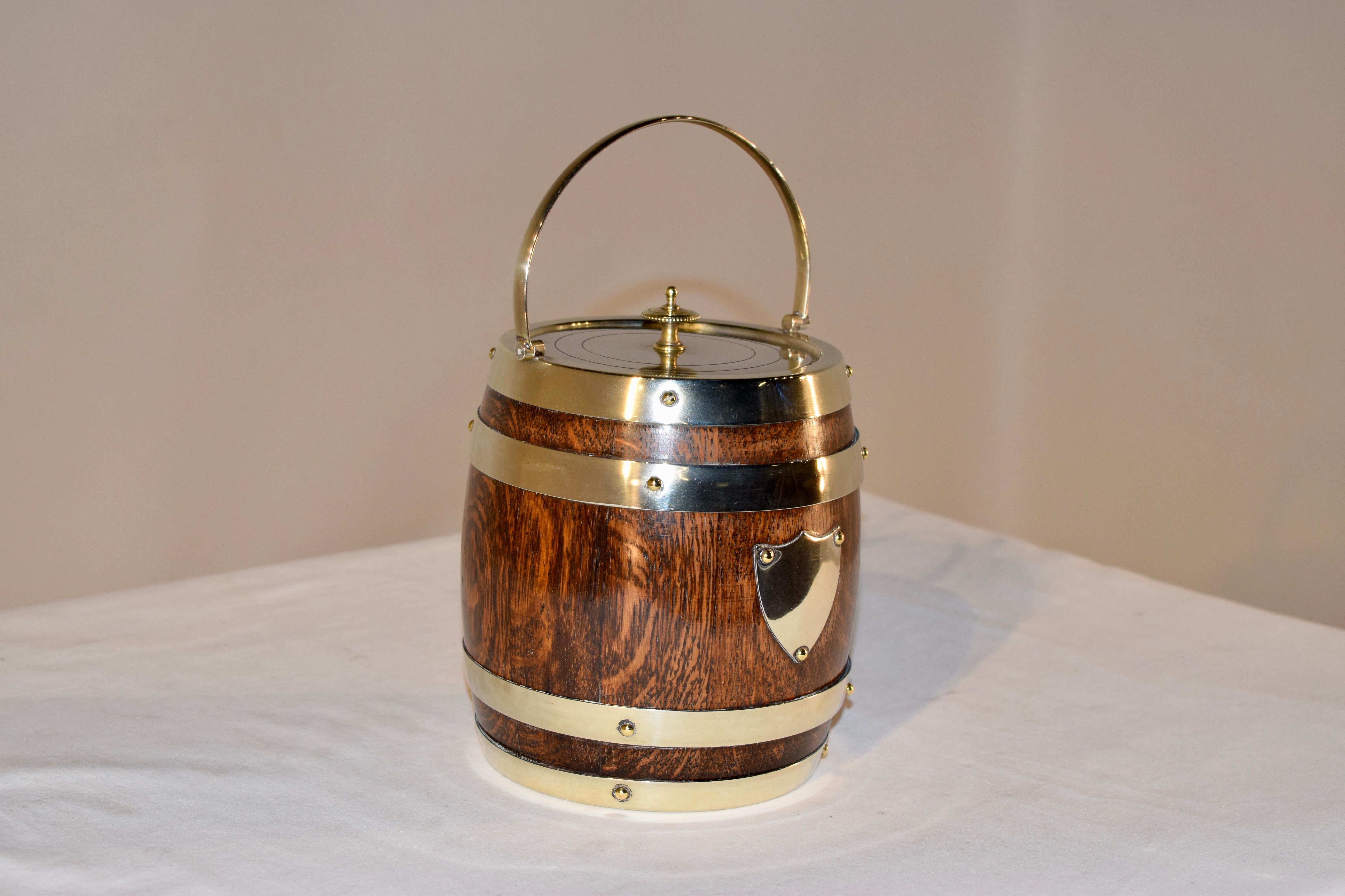 English oak biscuit barrel, made by Daniel and Arter of Birmingham. The barrel is made from oak and retains the original porcelain liner, and is strapped with silver plated bands, as well as a silver plated handle, lid, collar and bottom band.