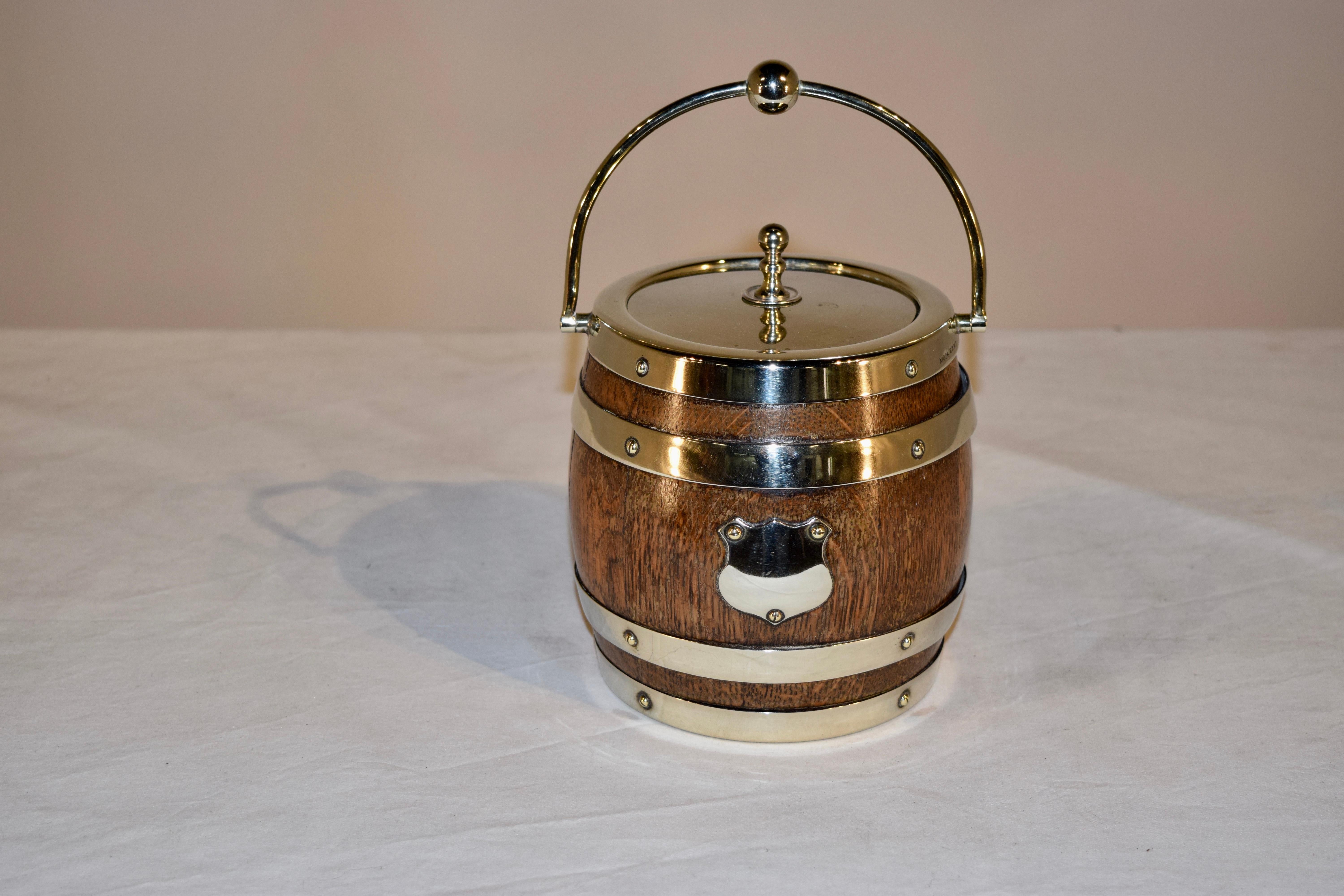 Nice biscuit barrel made of oak from England with the original porcelain liner and silver plated straps, lid and plaque. Silver finish is rubbed thin from years of polishing.