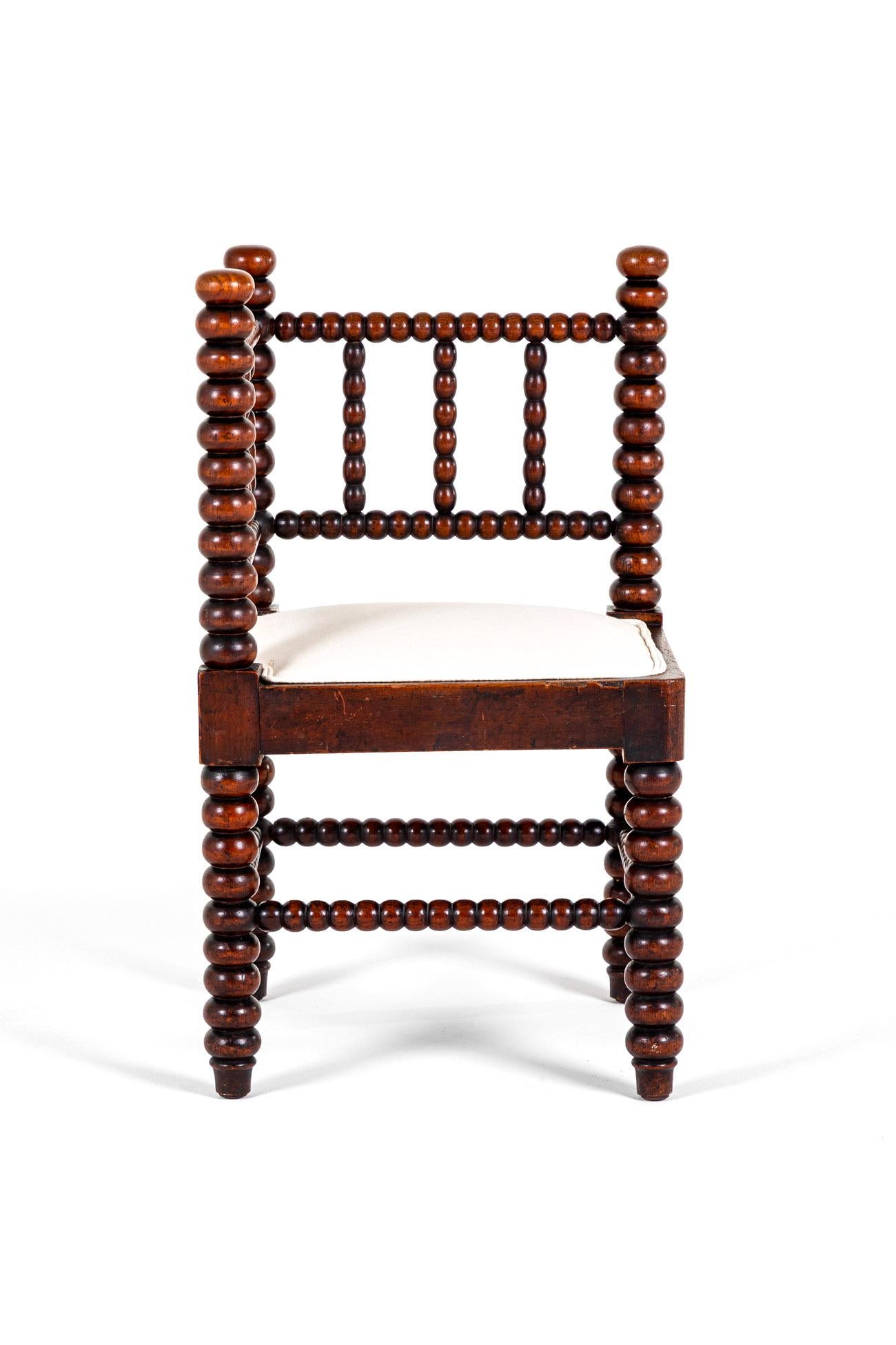 A superb oversized Victorian bobbin corner chair in oak with a freshly upholstered calico seat cushion.

The double railed ladder back rest with six turned splats adjoined to oversized wood and ball turned uprights.

Chunky turned wooden legs united
