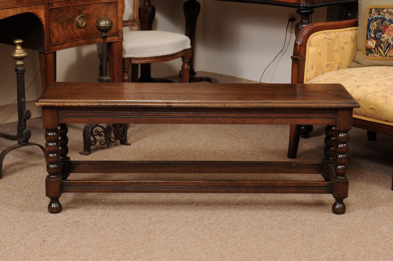 A late 19th century English oak bench featuring bobbin turned legs joined by box stretcher ending in turned round feet. 

 