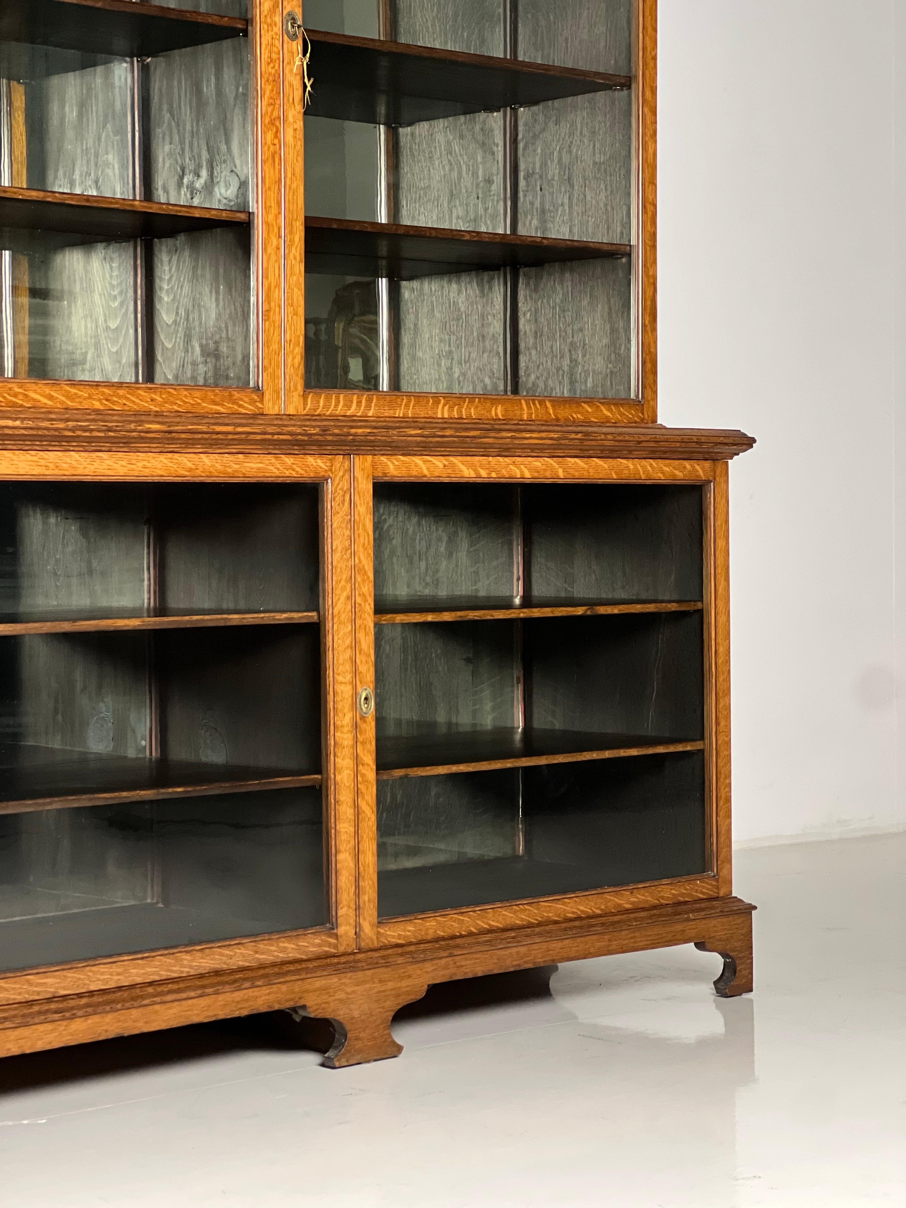 Solid oak display cabinet / bookcase / sideboard. Originally from England, 2nd half of the 19th century. The entire back wall has a mirror that is slightly weathered. The cabinet is in almost perfect condition. Contains original antique glass and